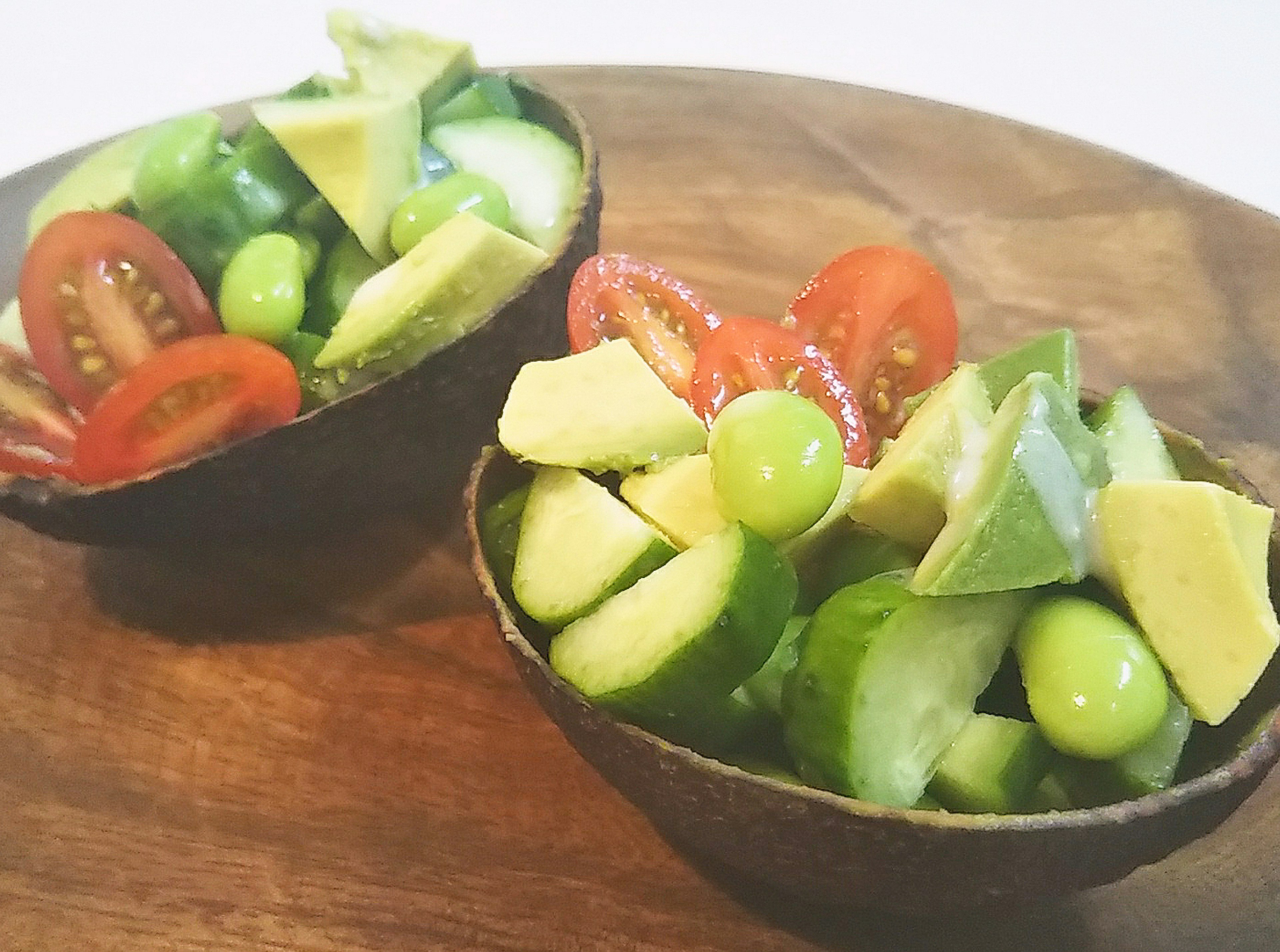 Insalata fresca servita in ciotole di avocado con pomodorini, cetrioli, uva verde e lime