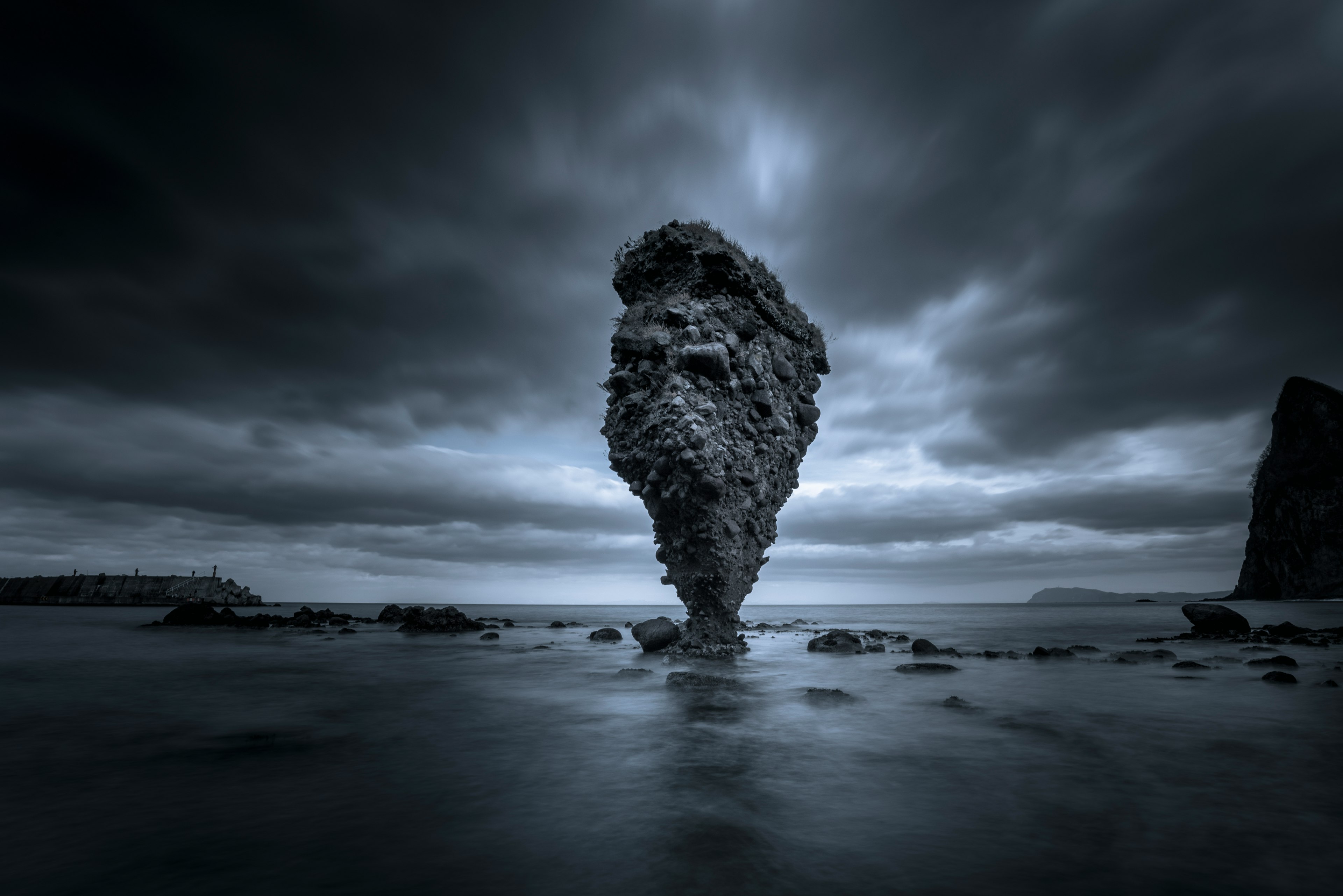 Isolated rock formation surrounded by dark sea and clouds