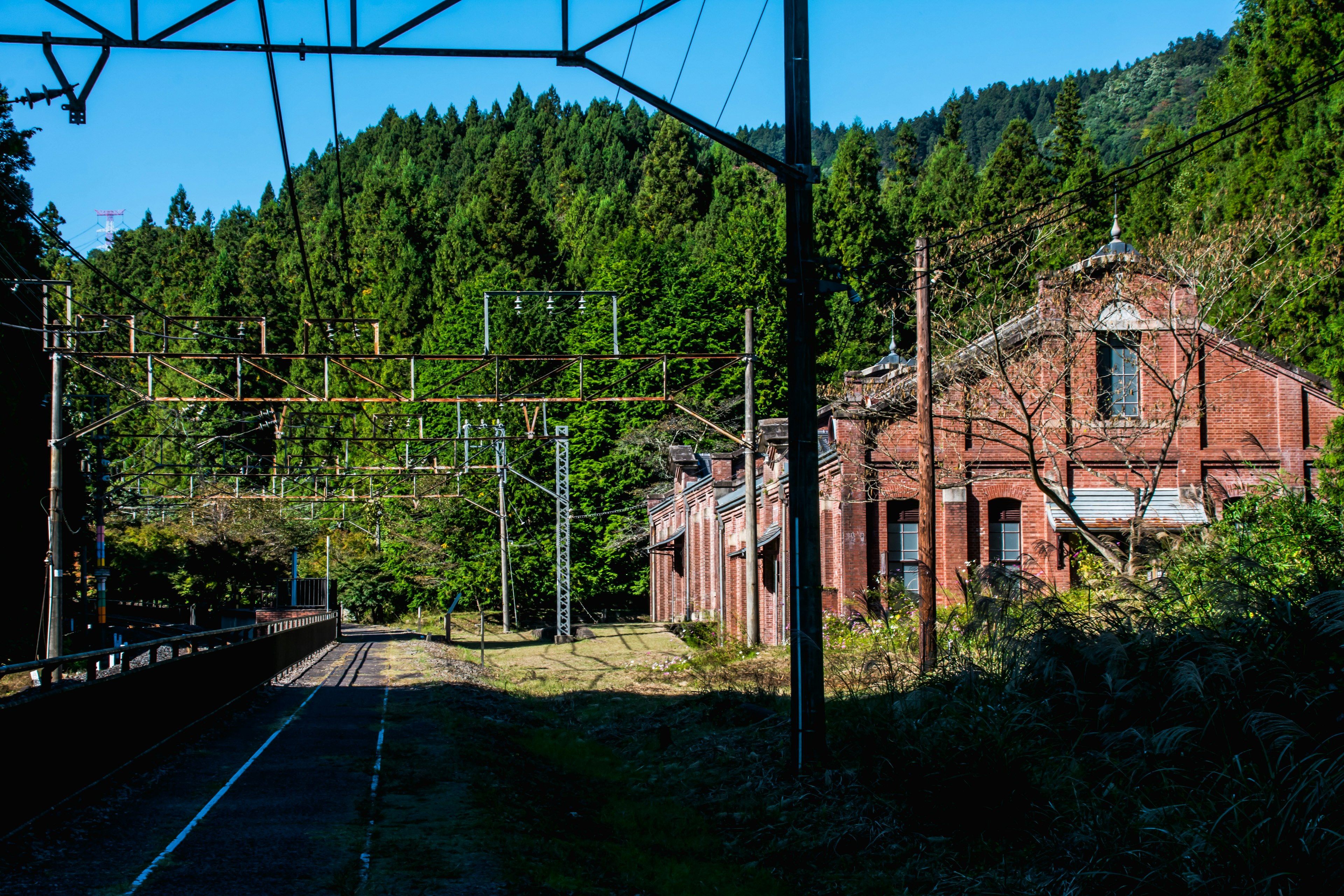 Vecchia stazione ferroviaria in mattoni circondata da montagne verdi