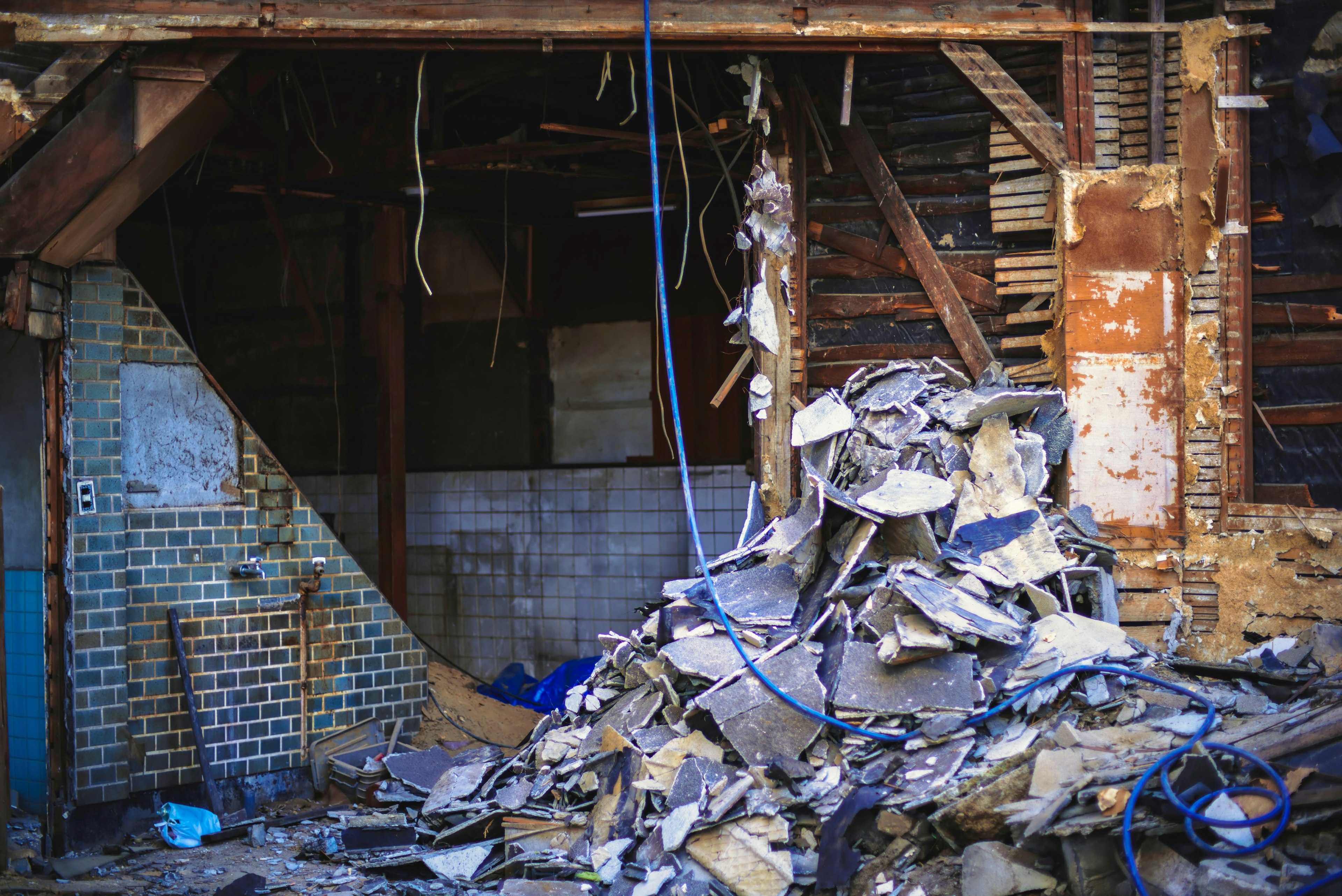 Piled debris inside a dilapidated building with exposed walls