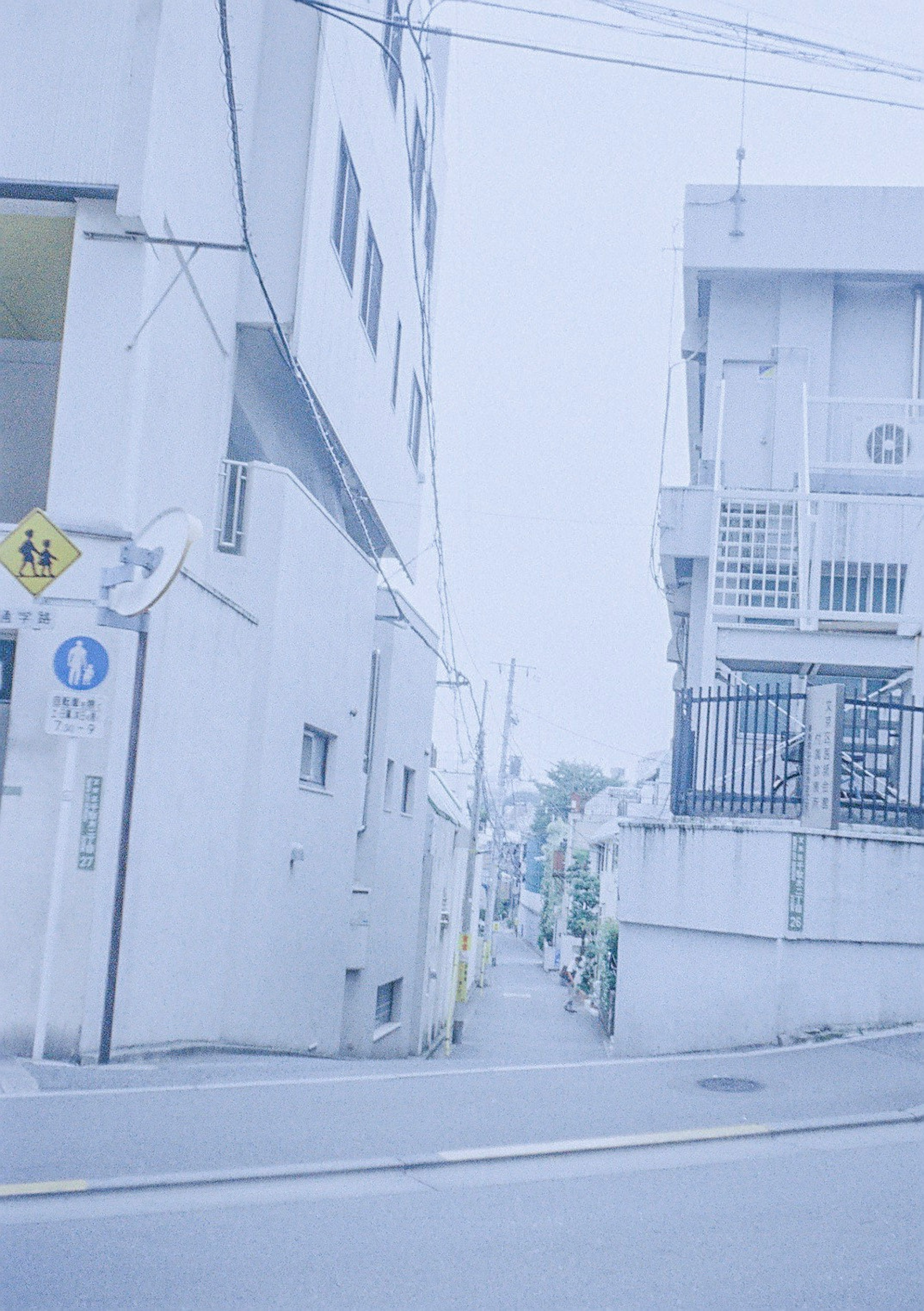 Narrow street scene with pale blue buildings and overhead wires