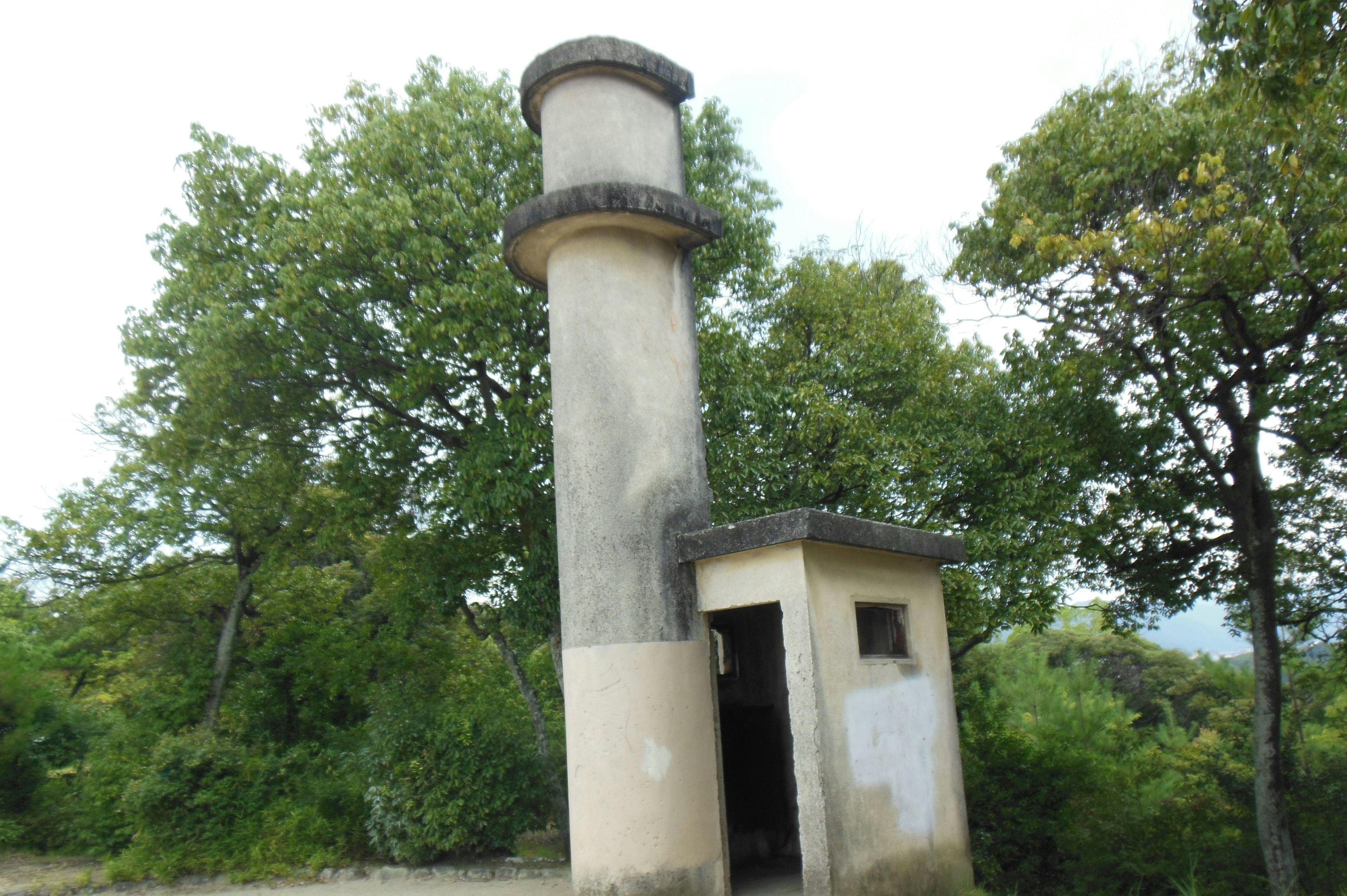 Old tower and small structure surrounded by green trees