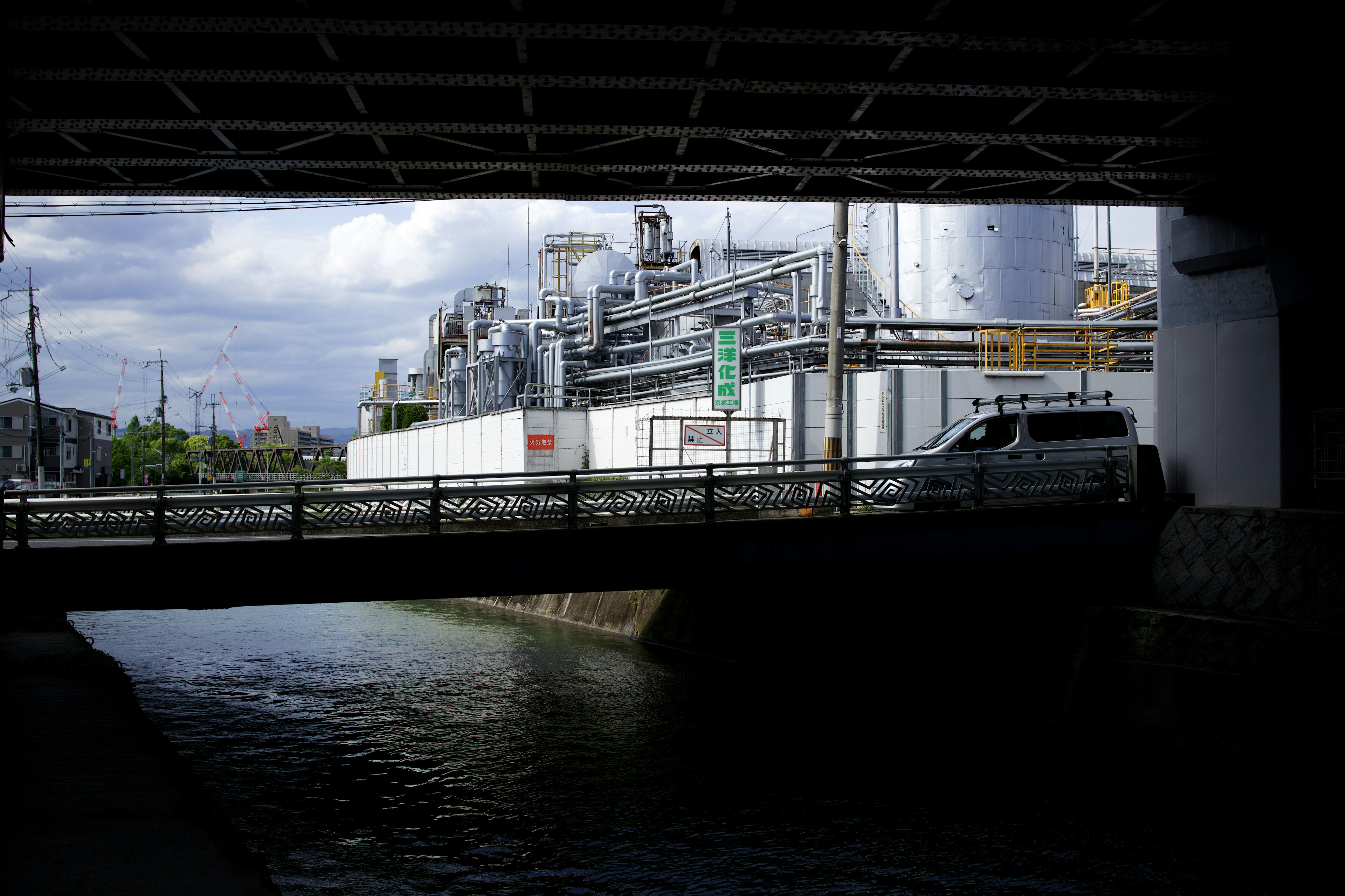 Industrielandschaft von unter einer Brücke mit einem Gewässer aus gesehen