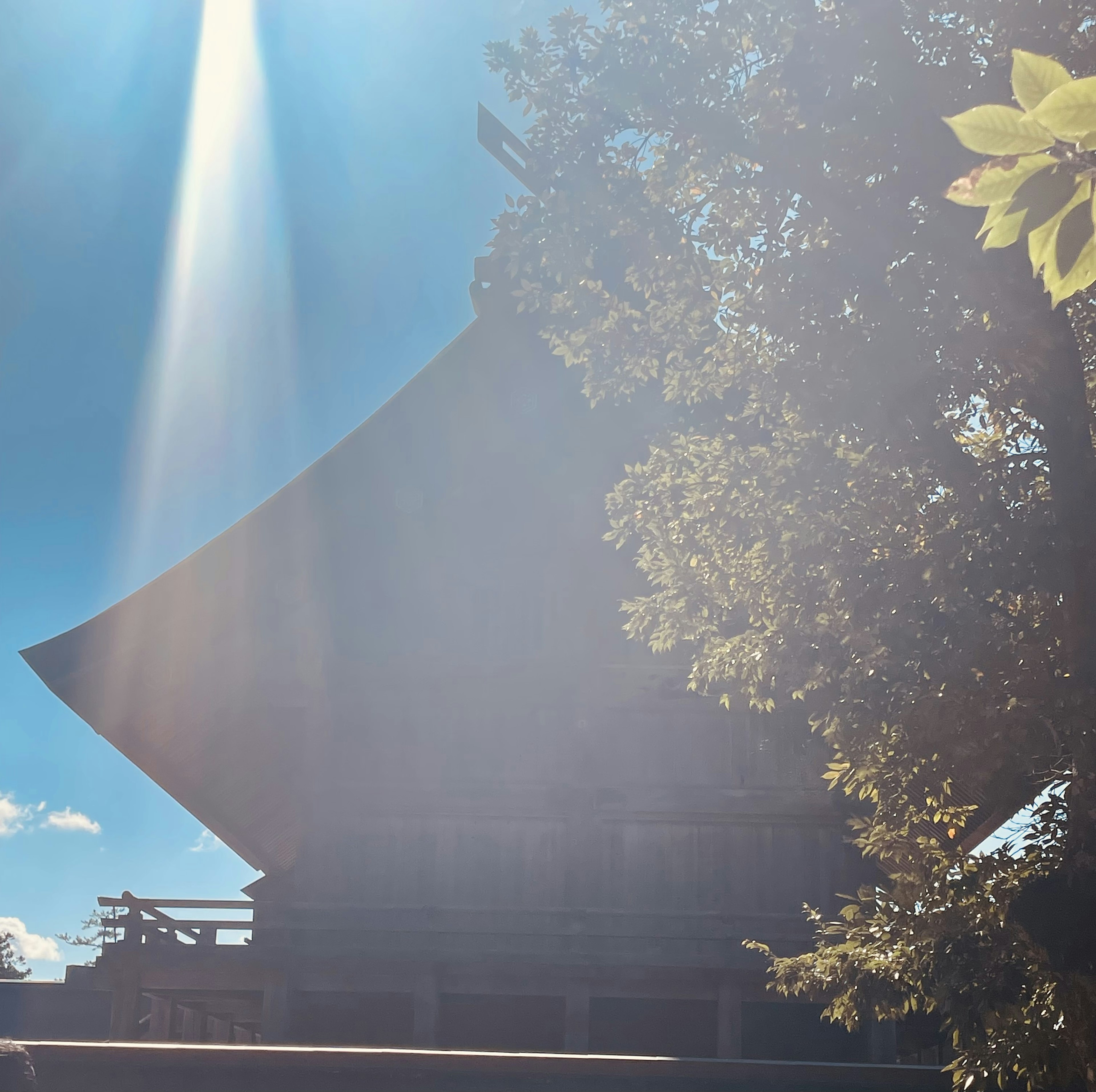 Silhouette of a traditional building under a blue sky with a beam of light in the background