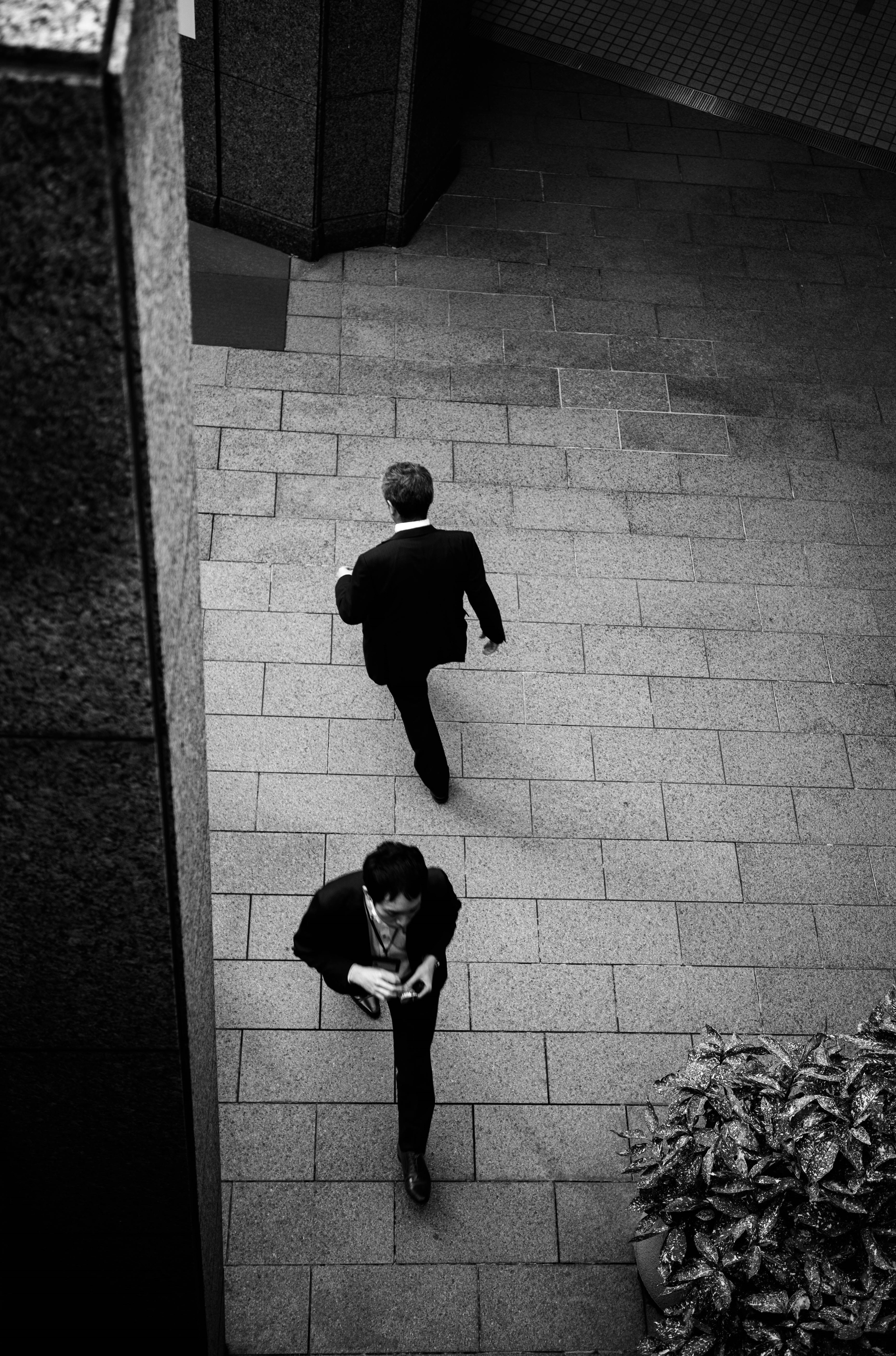 Escena urbana en blanco y negro con dos hombres en traje caminando