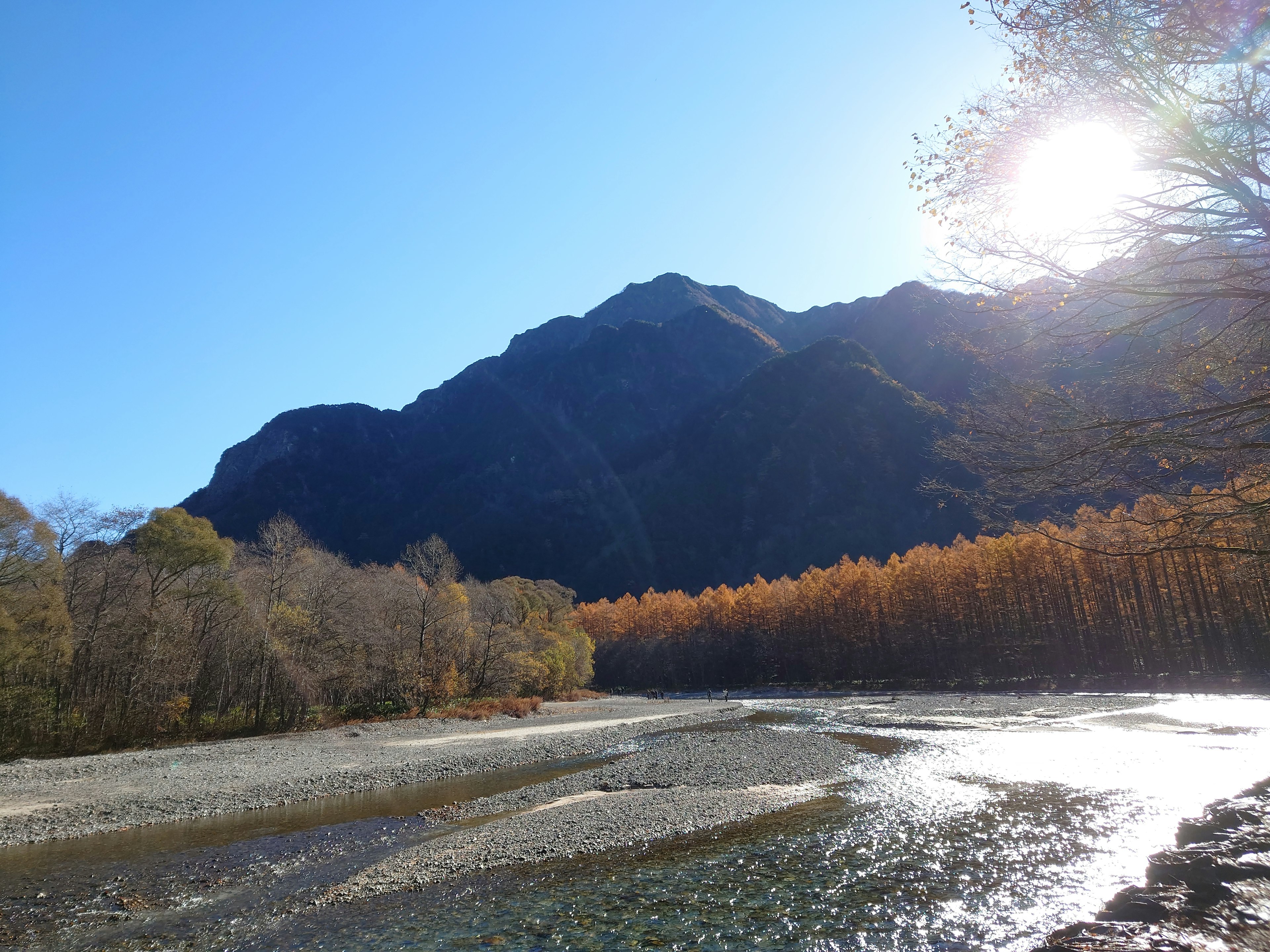 Scenic view of mountains and river with bright sun