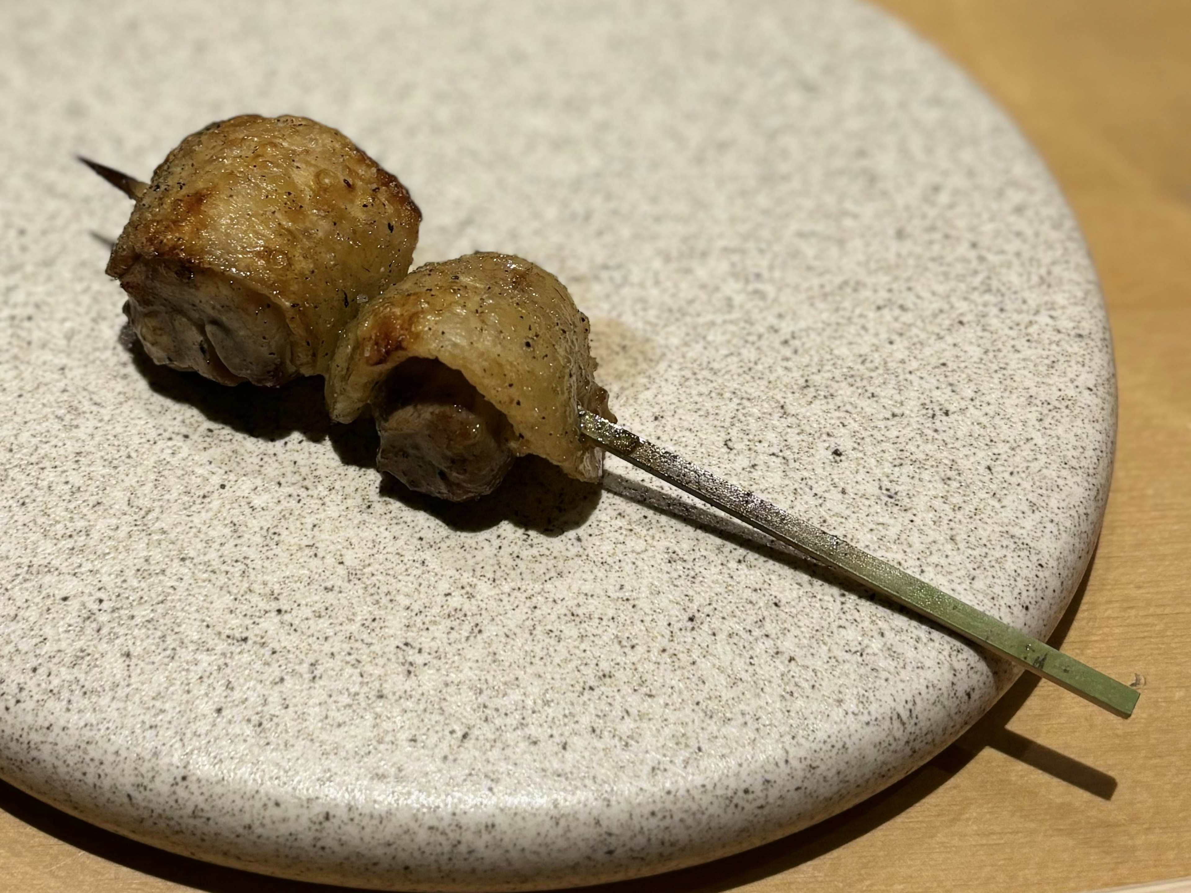 Grilled meat skewers placed on a textured plate