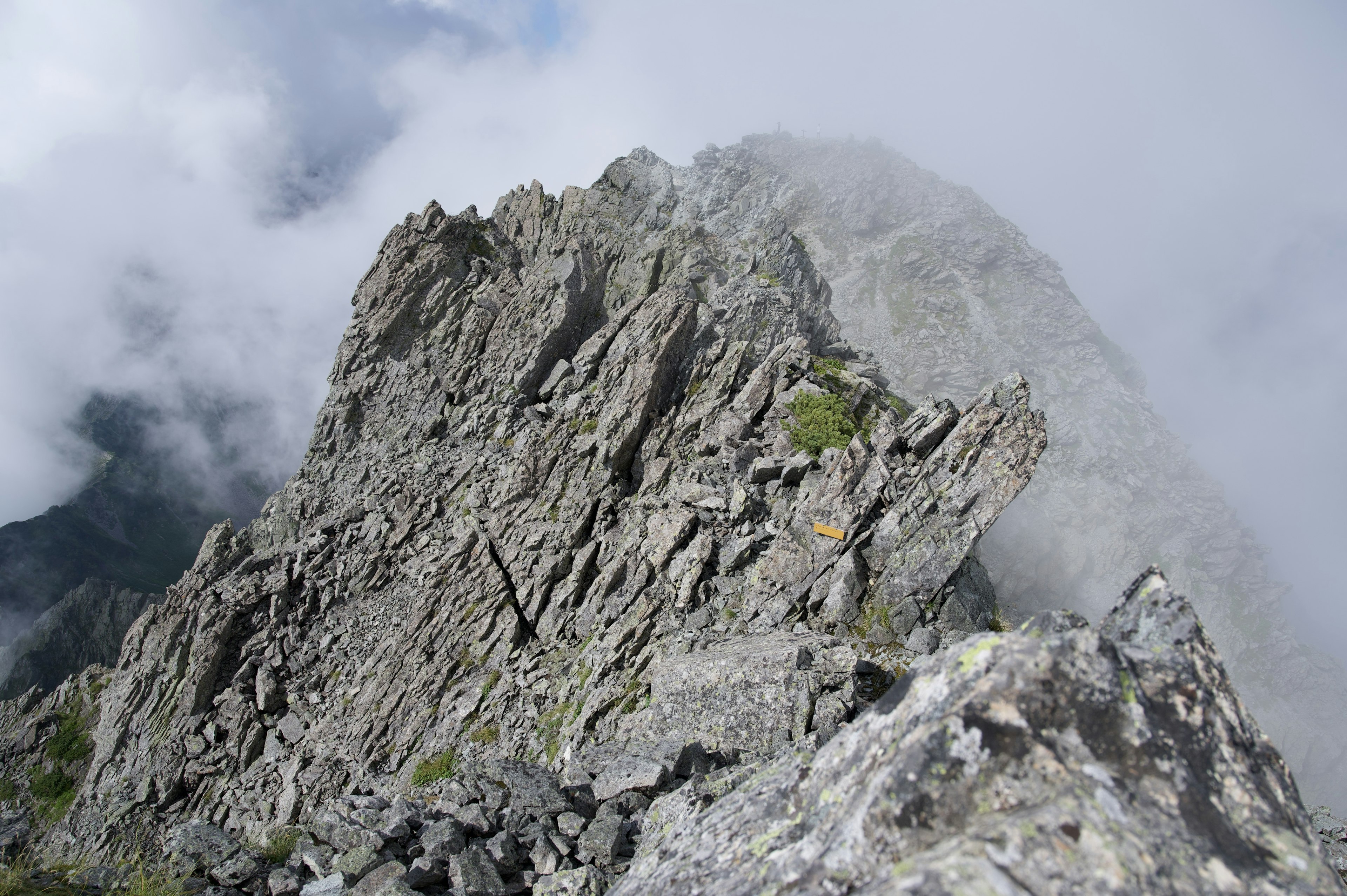 Jagged rocky peak shrouded in mist with clouds surrounding