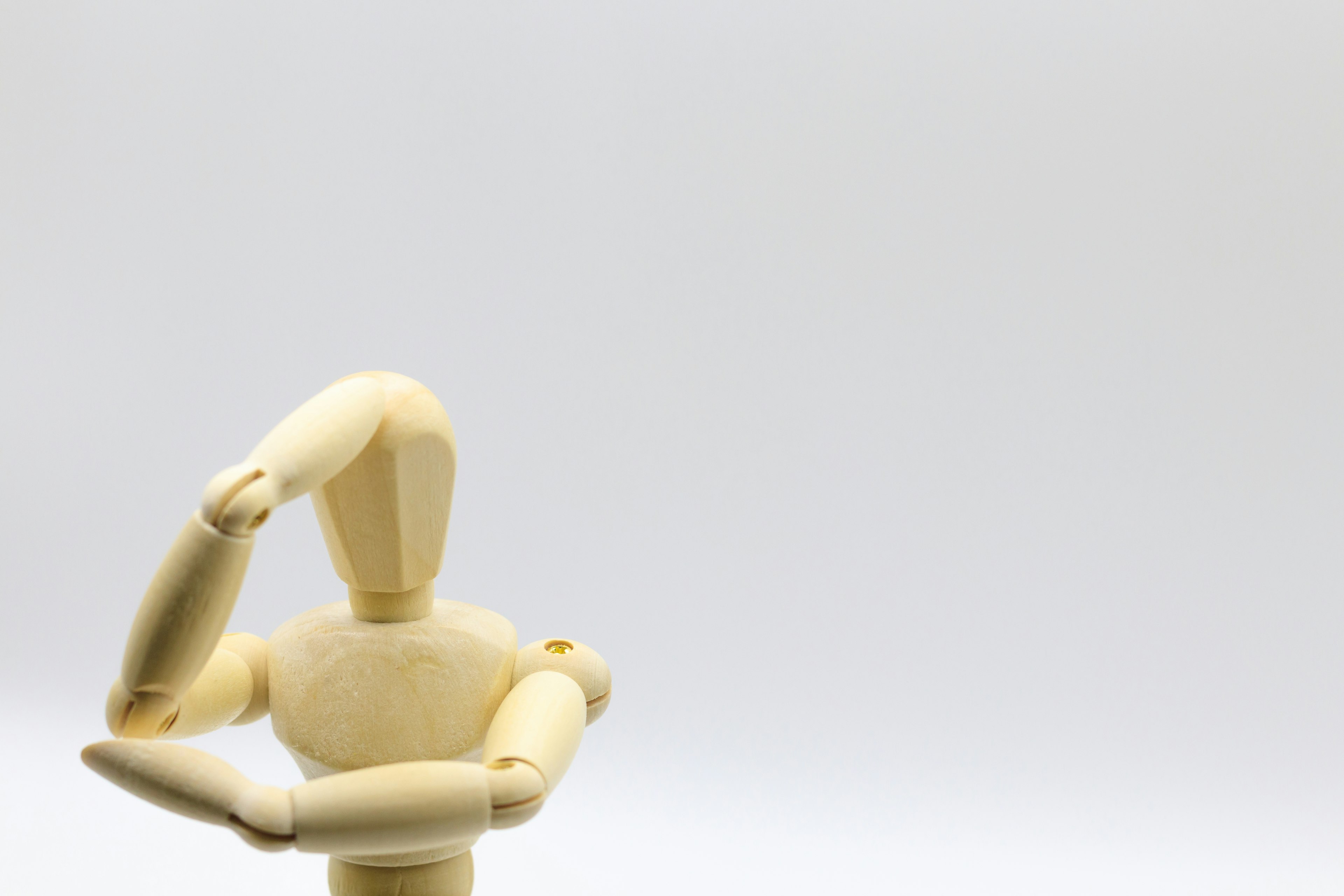 A wooden mannequin posing against a simple background