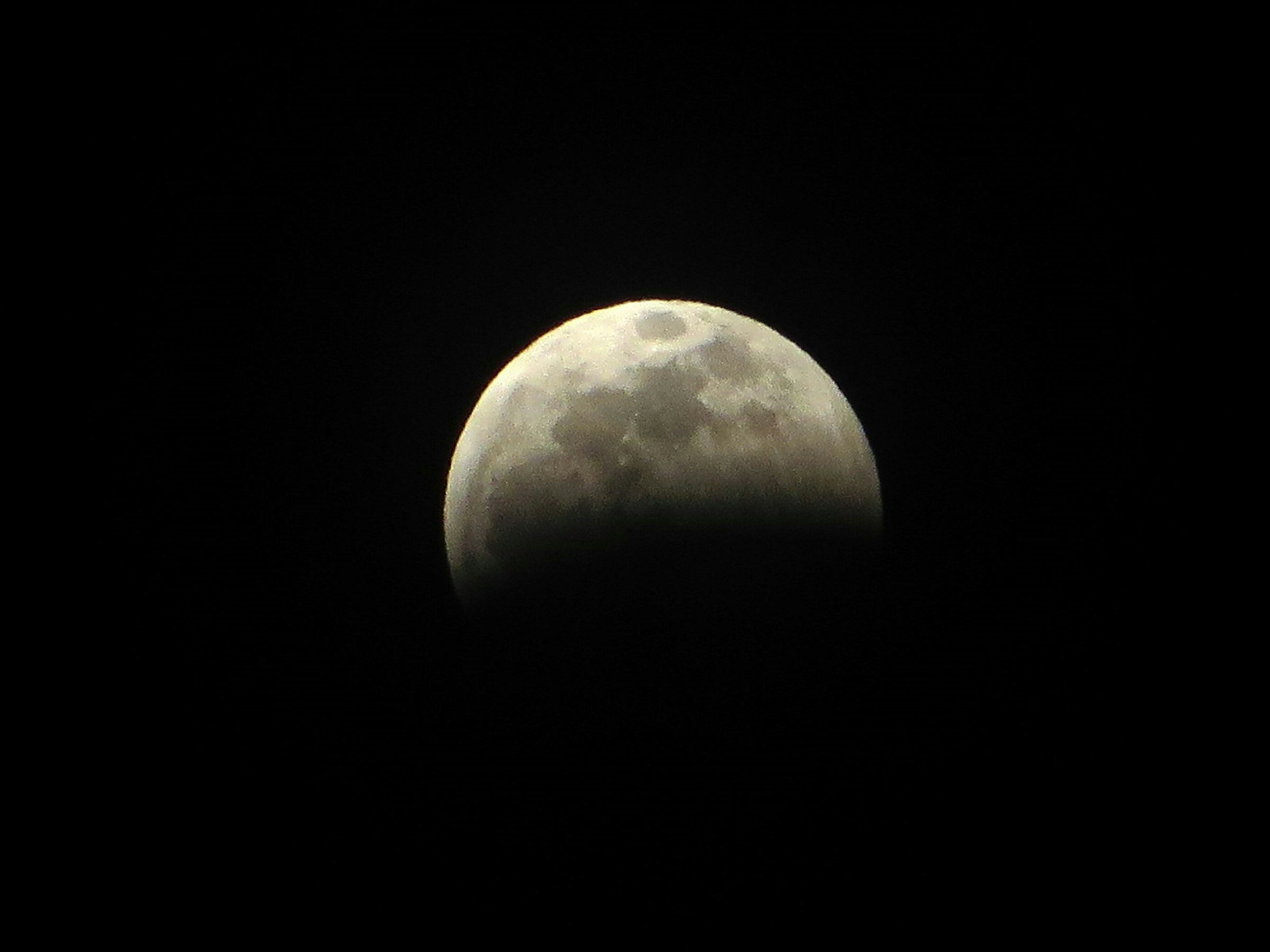 Luna parcialmente iluminada sobre un fondo oscuro