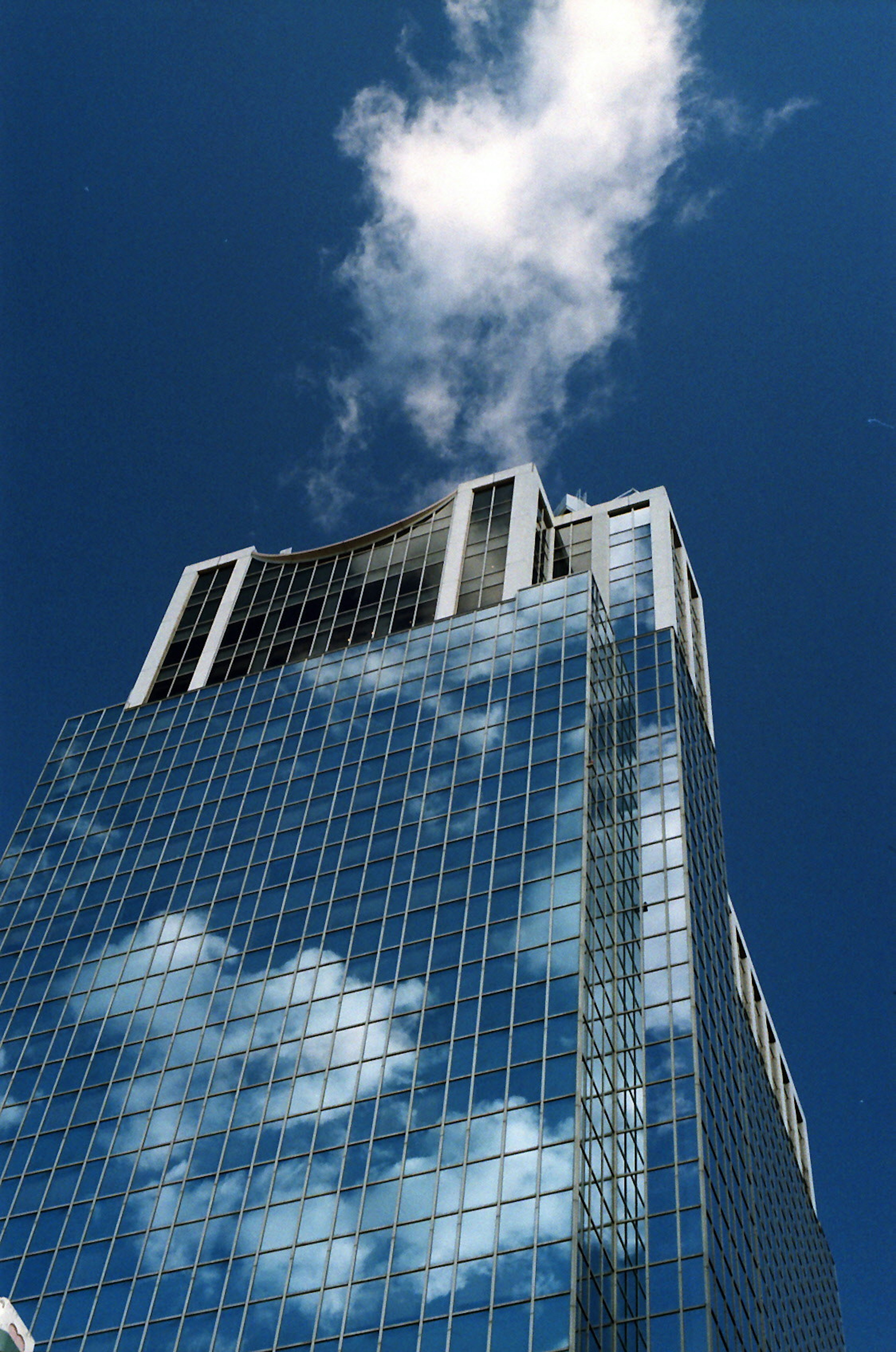 Rascacielos reflejando nubes bajo un cielo azul