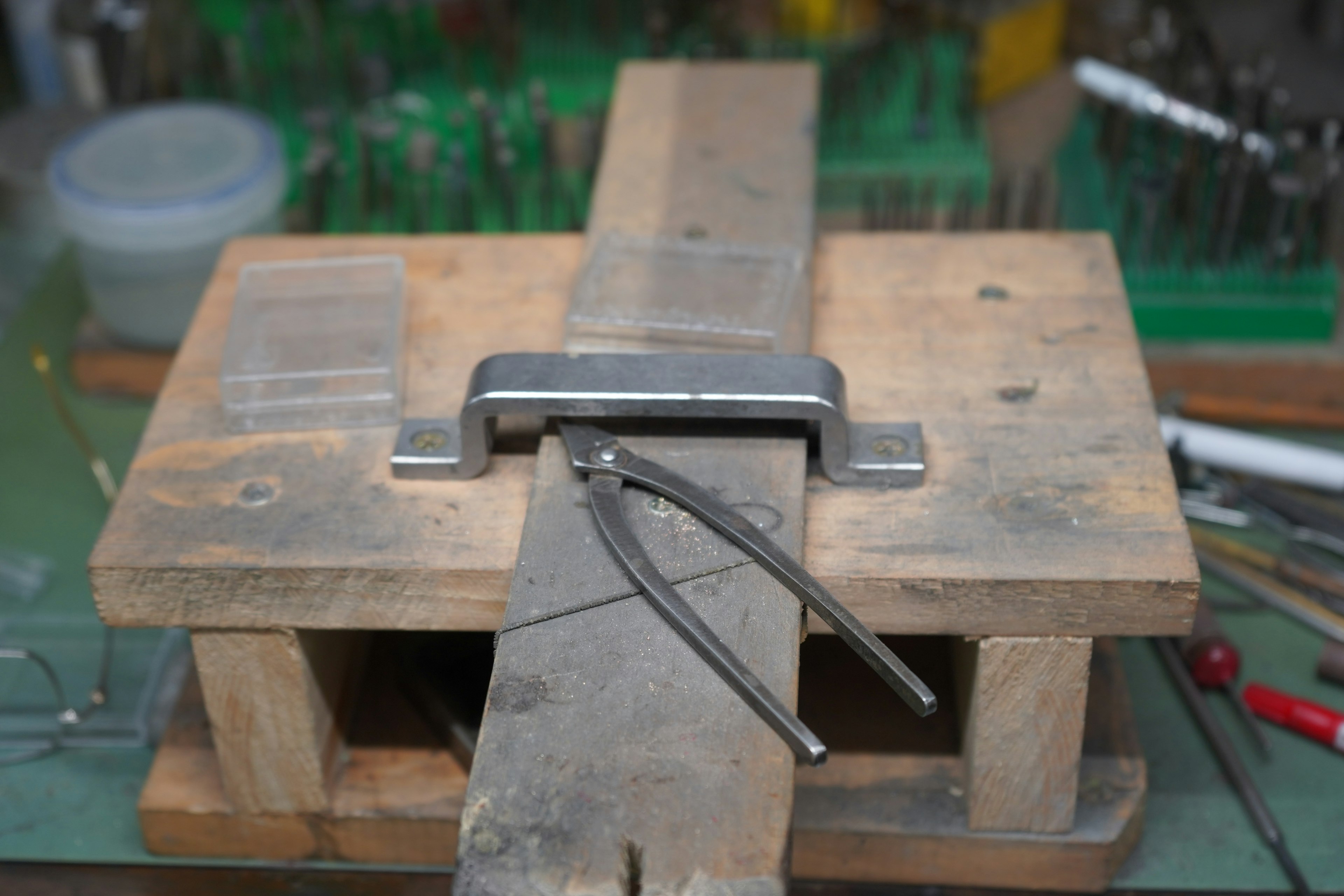 A wooden workbench featuring a metal clamp and tools arranged on top