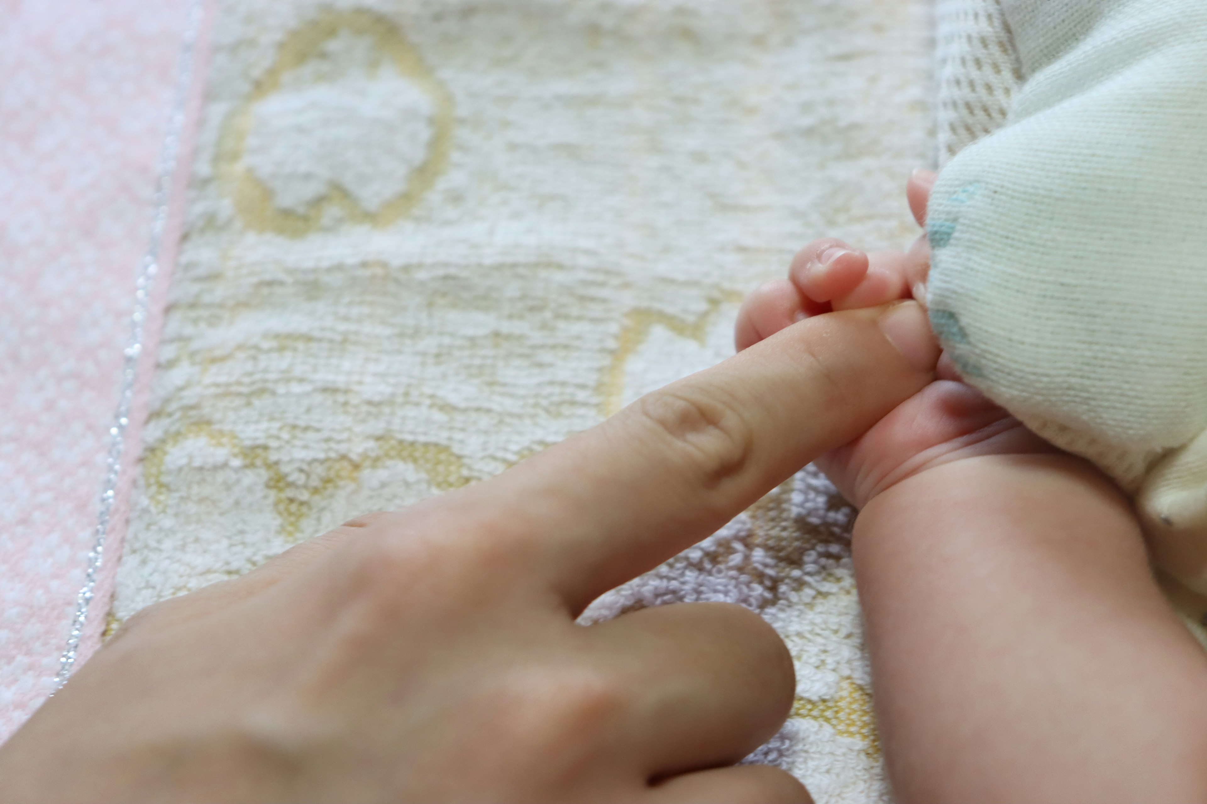 A close-up of an adult finger touching a baby's hand