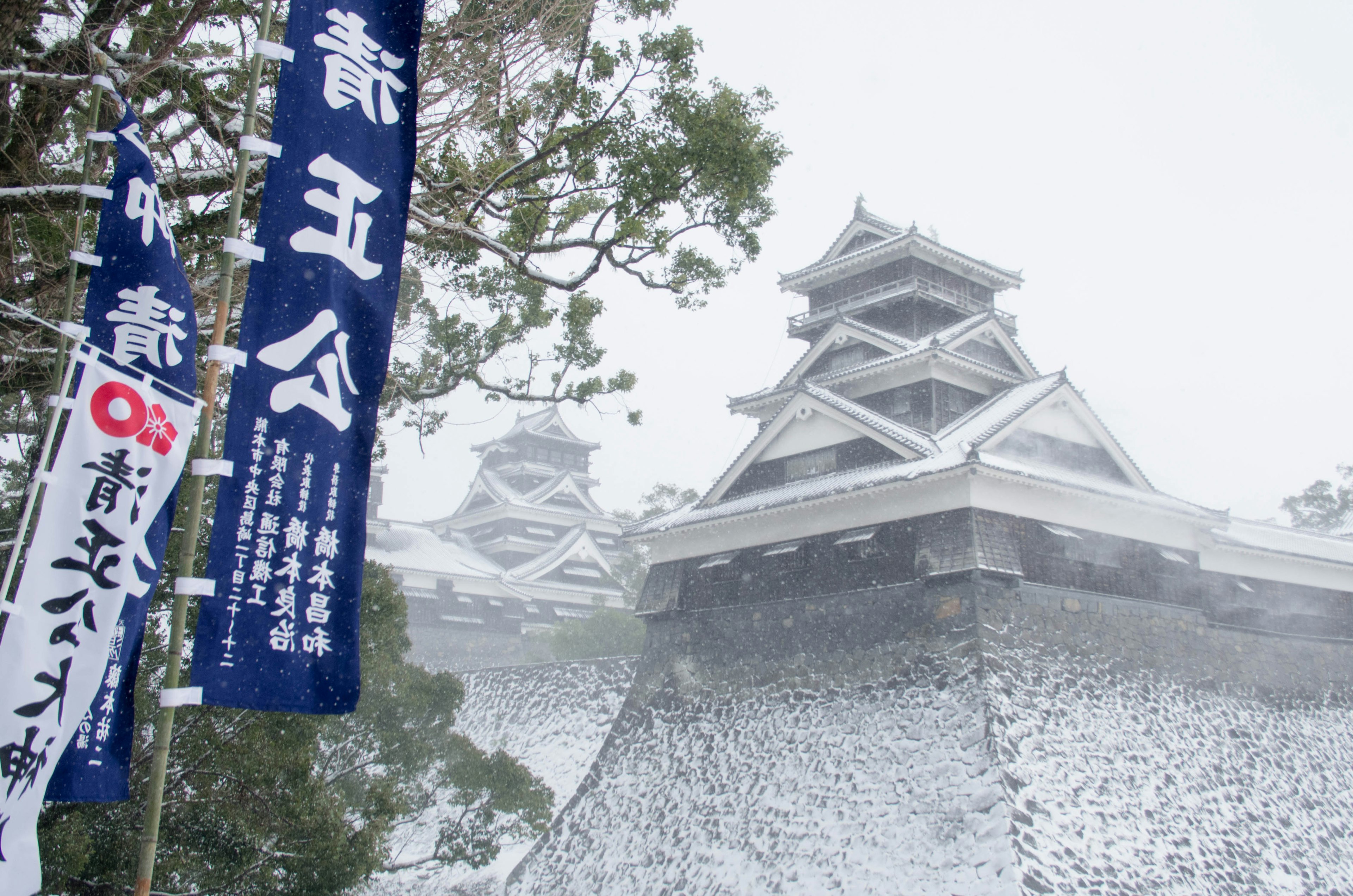 Bellissima vista del castello di Matsumoto coperto di neve con bandiere blu