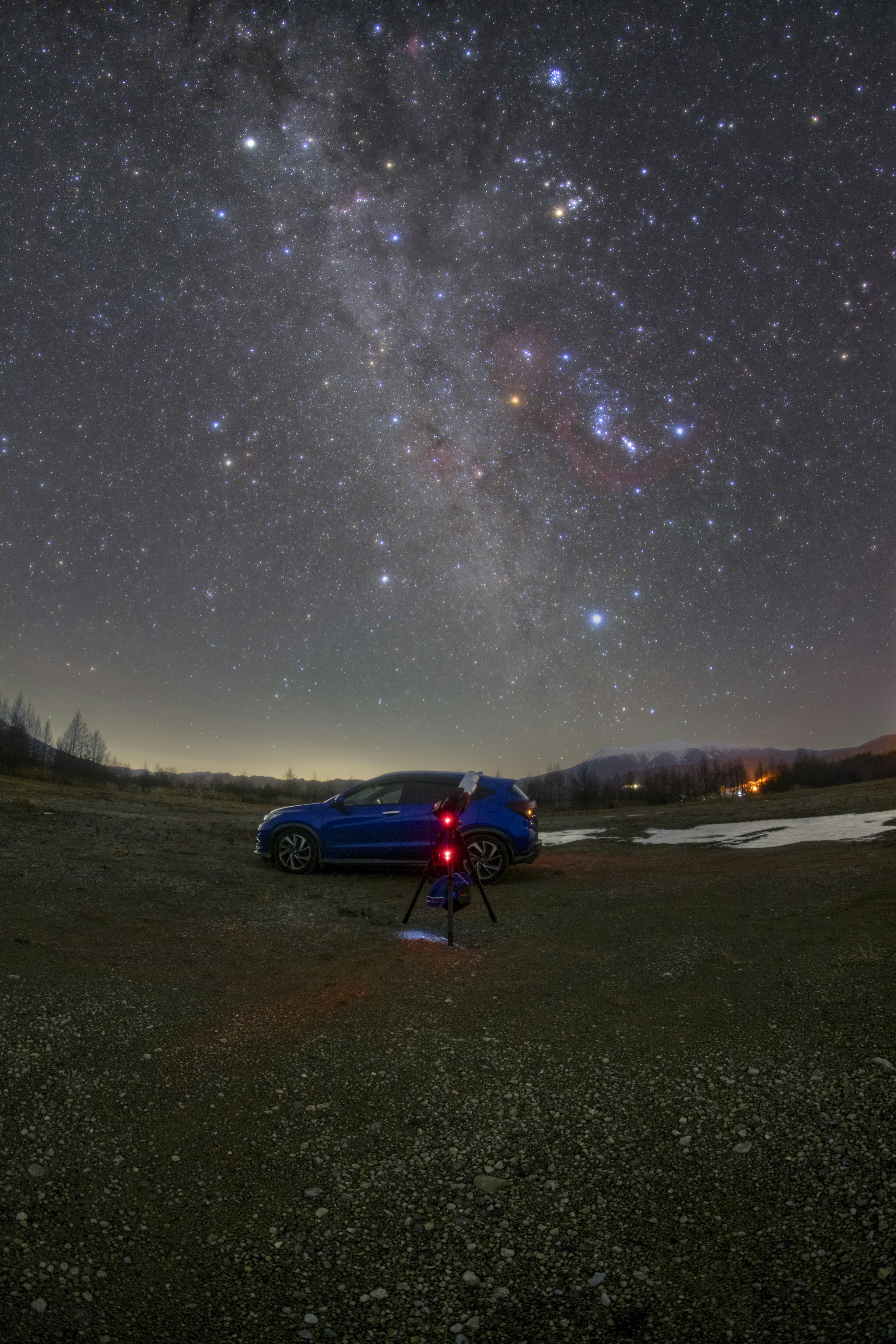 星空の下に青い車と星を観察する人