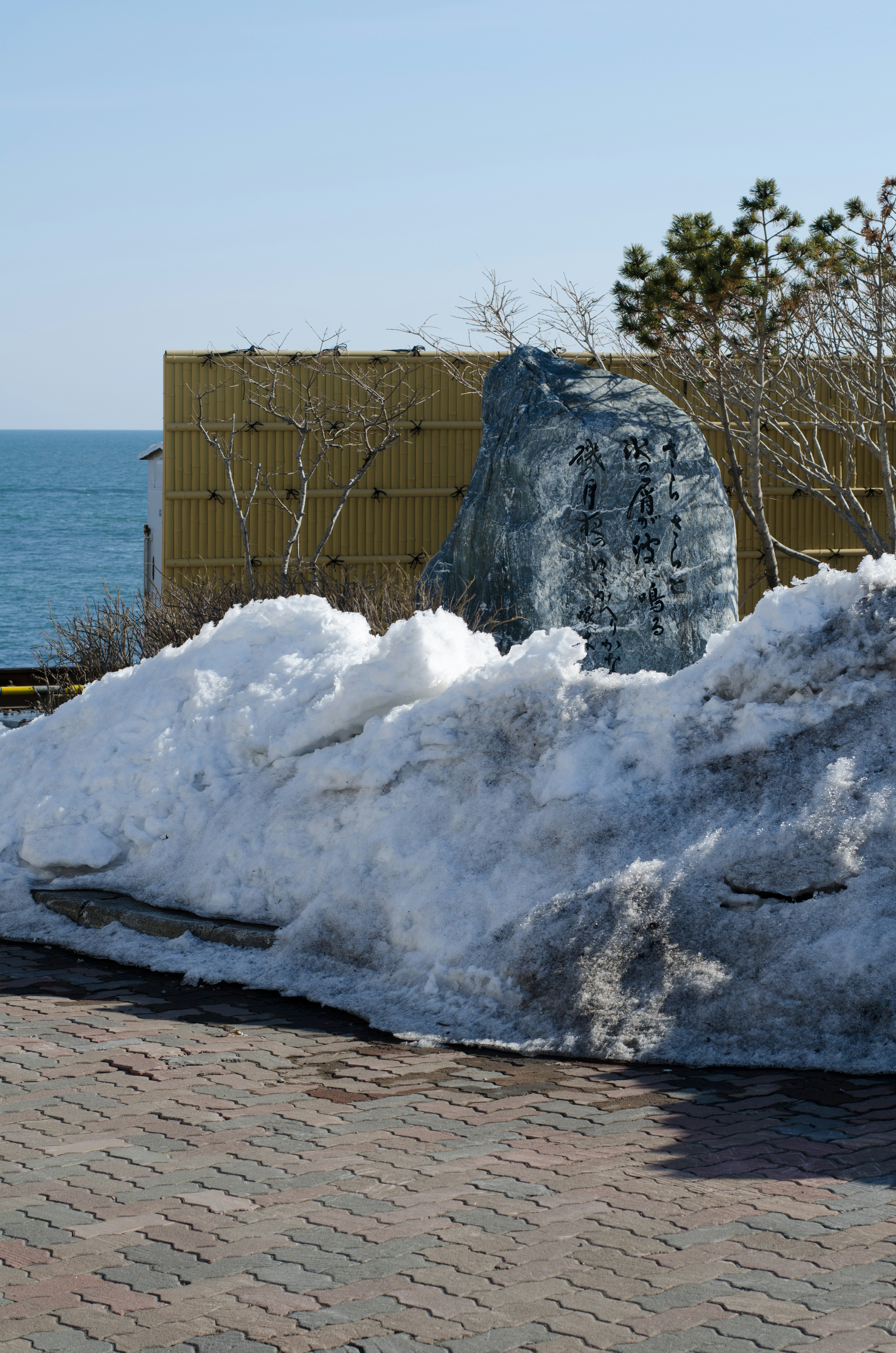 Un cumulo di neve con un mare blu sullo sfondo e una formazione rocciosa