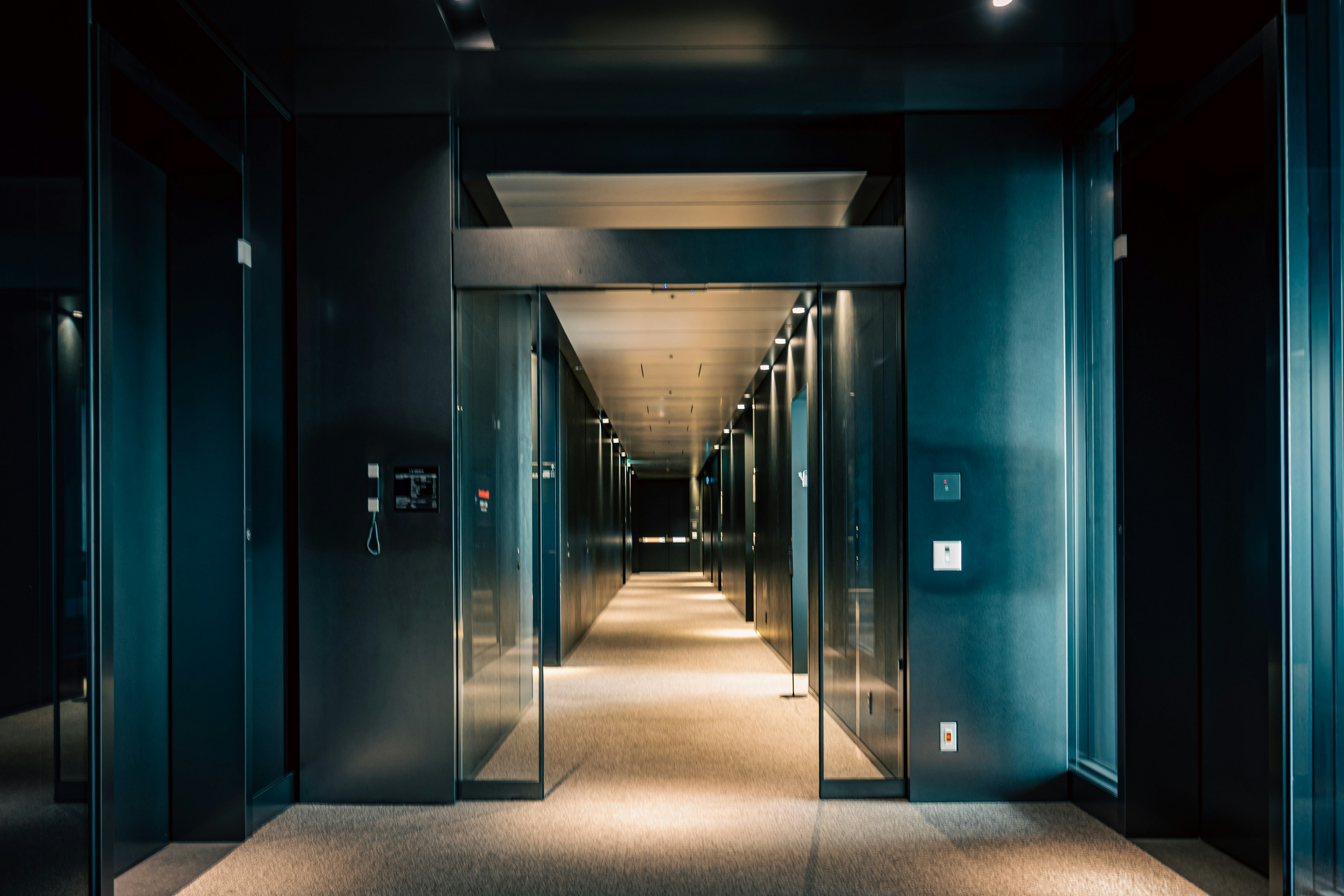 Modern hotel corridor with dark tones and reflective surfaces