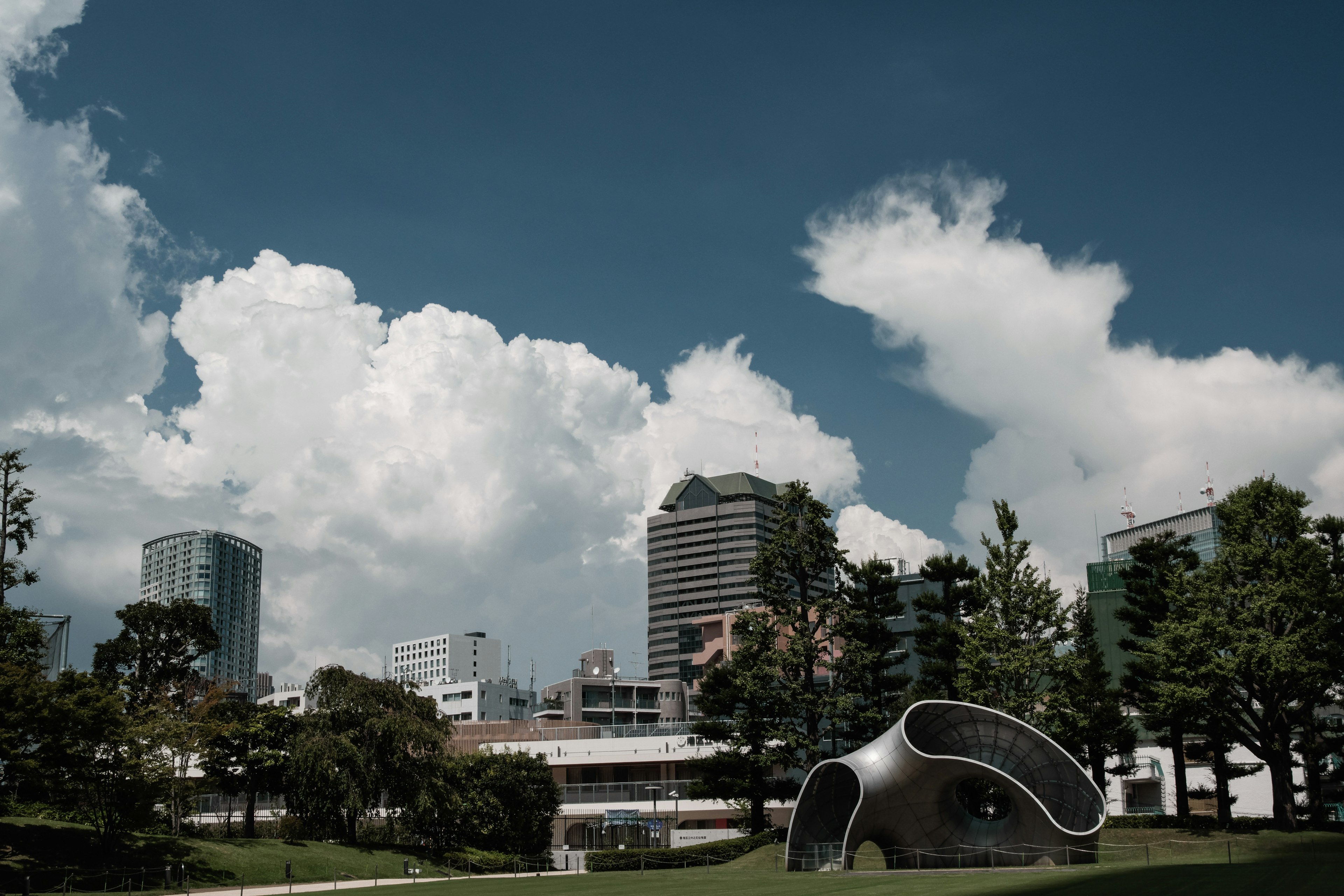 Moderne Skulptur in einem Park mit blauem Himmel und weißen Wolken