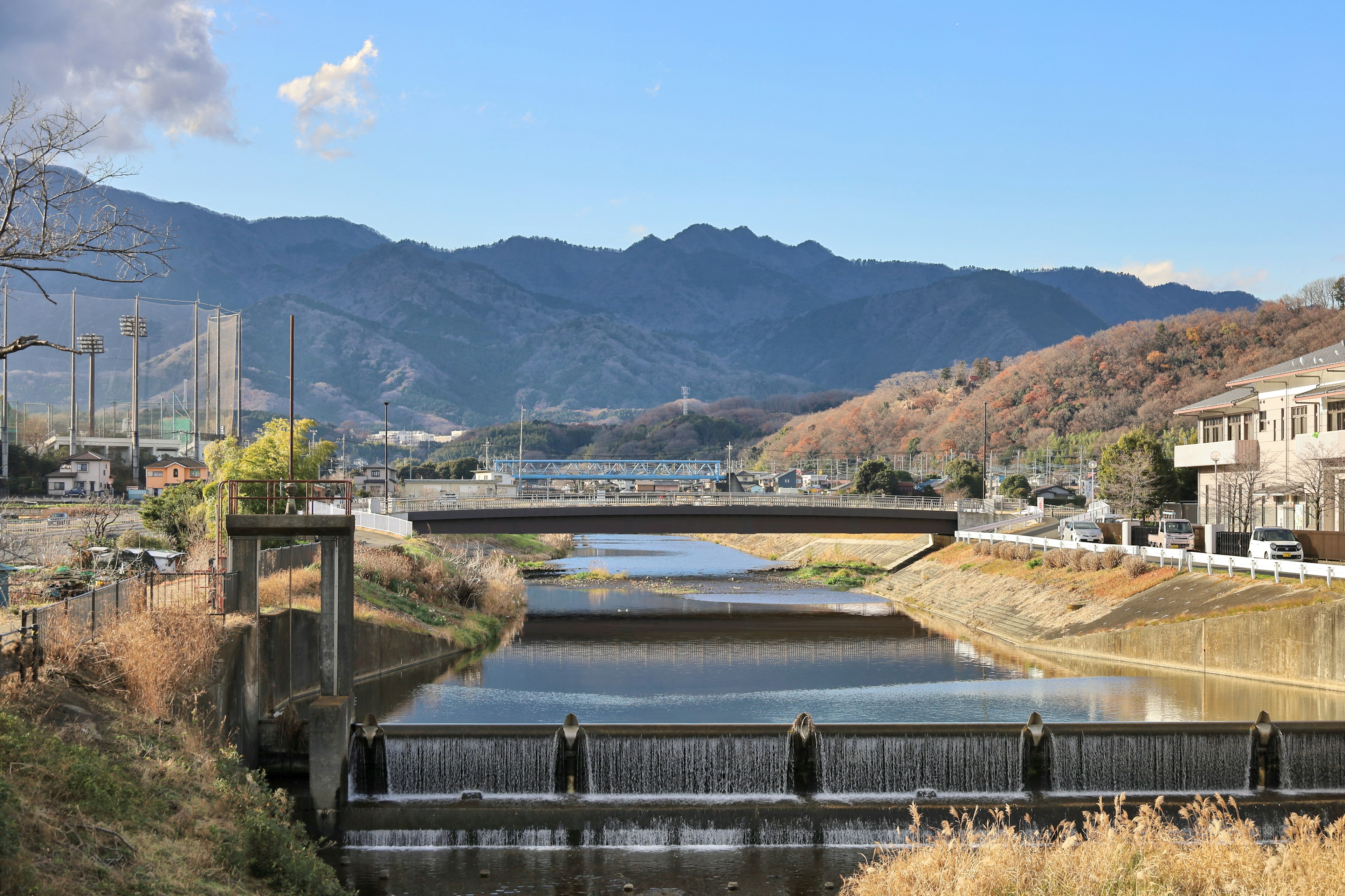 Scenic view of a river and mountains under a blue sky featuring a bridge and buildings