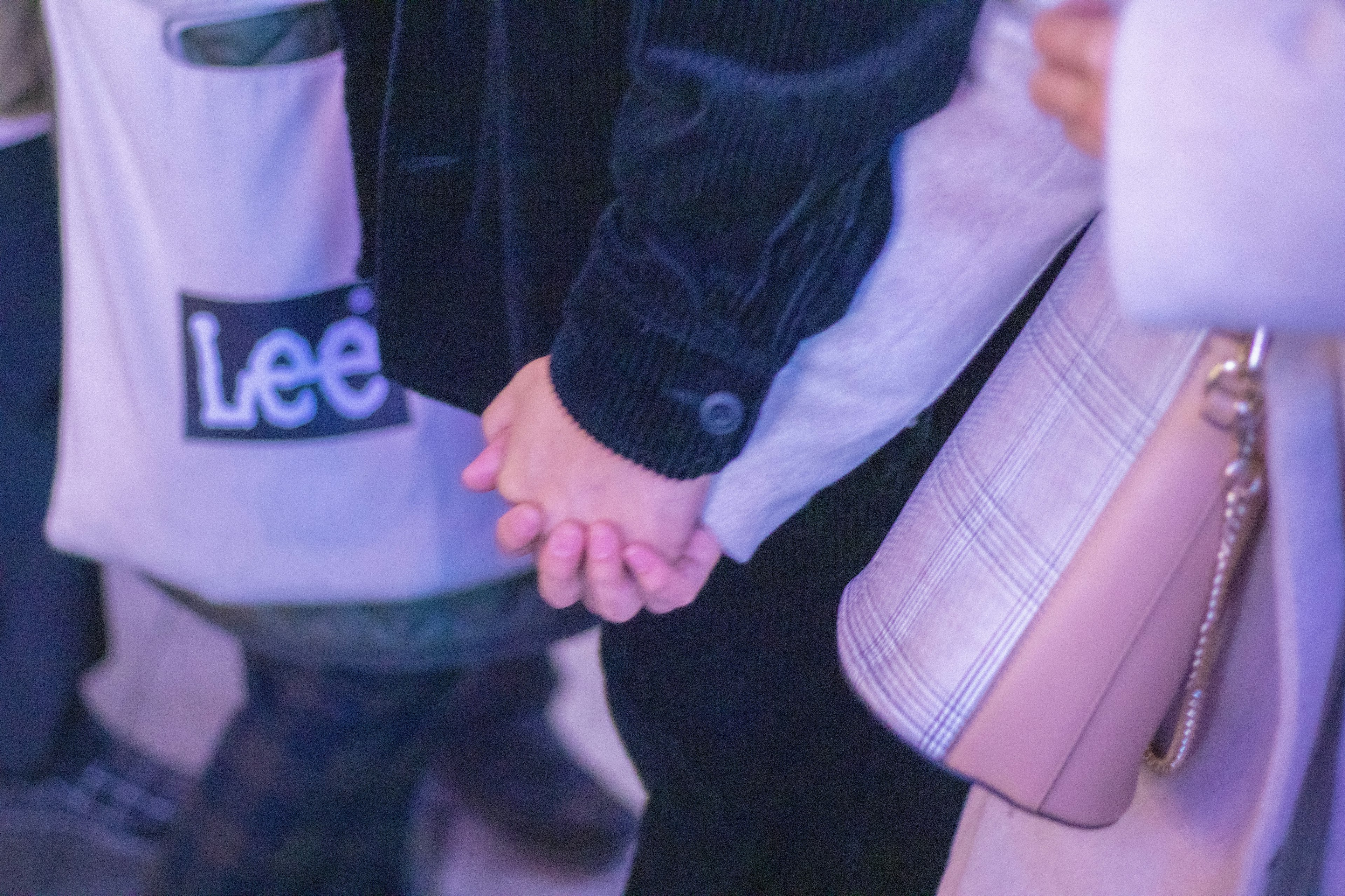 A photo of a couple holding hands with other people in the background