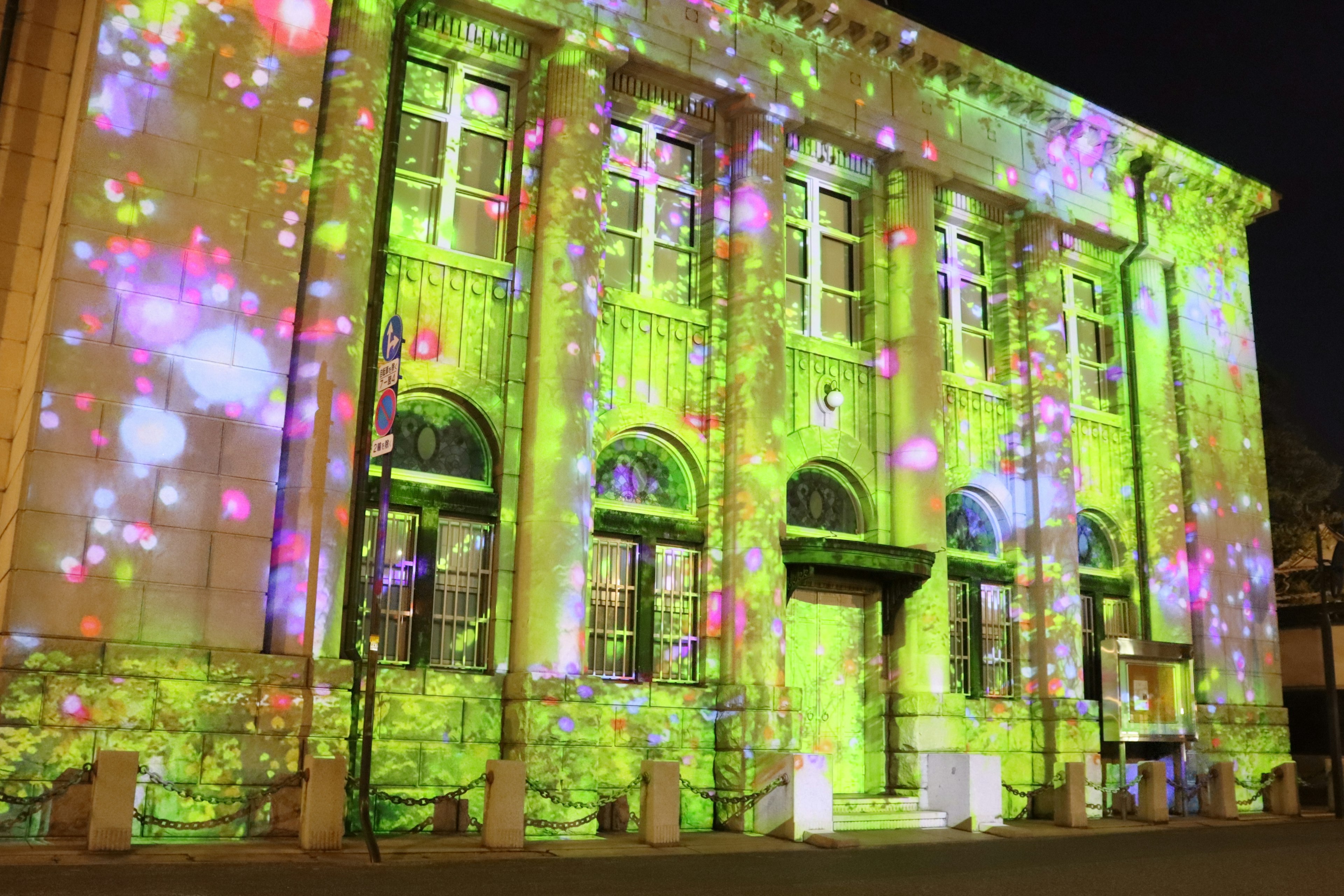 Edificio histórico iluminado con proyecciones de luces coloridas por la noche