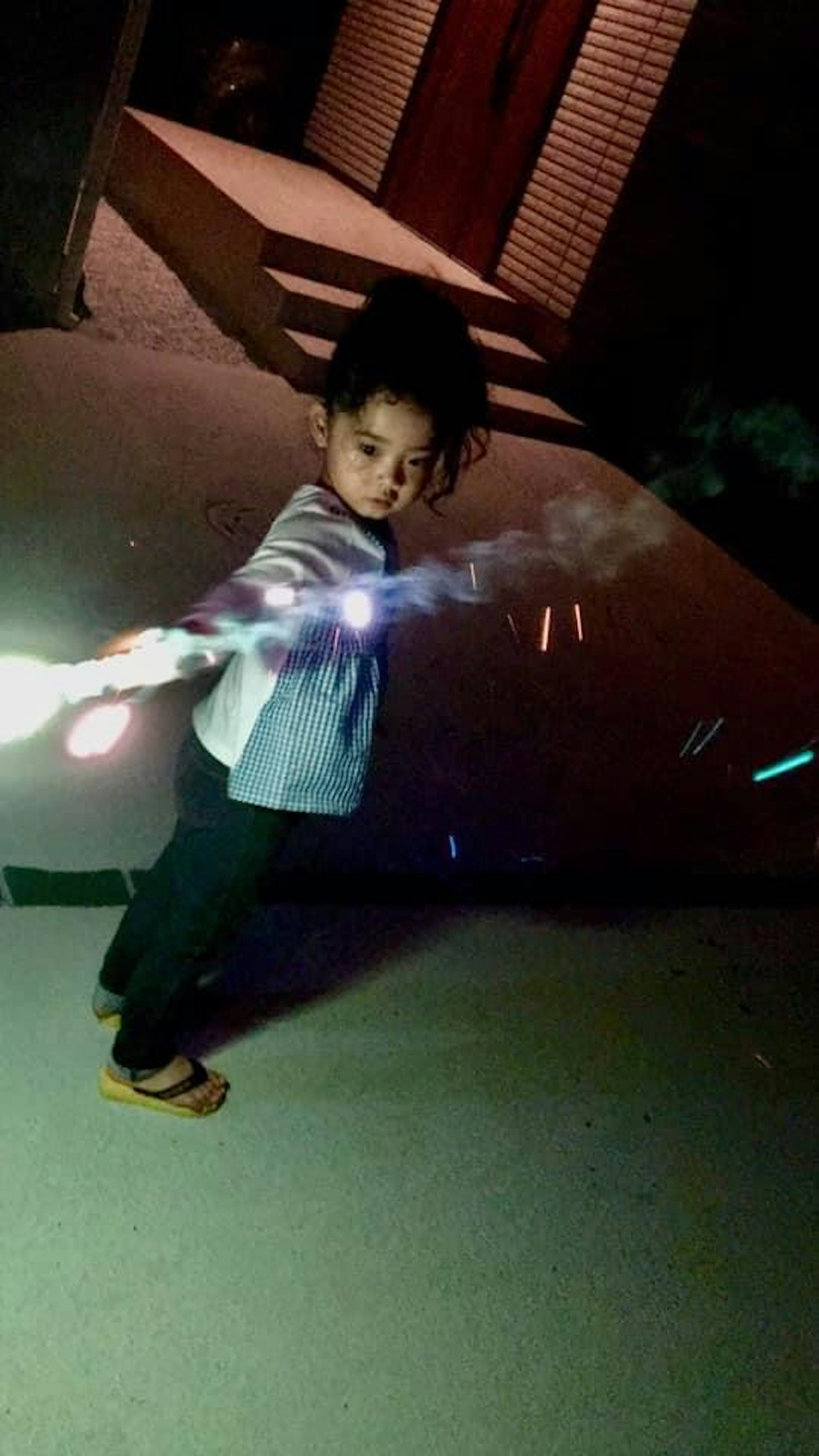 Child playing with a light stick in a nighttime setting