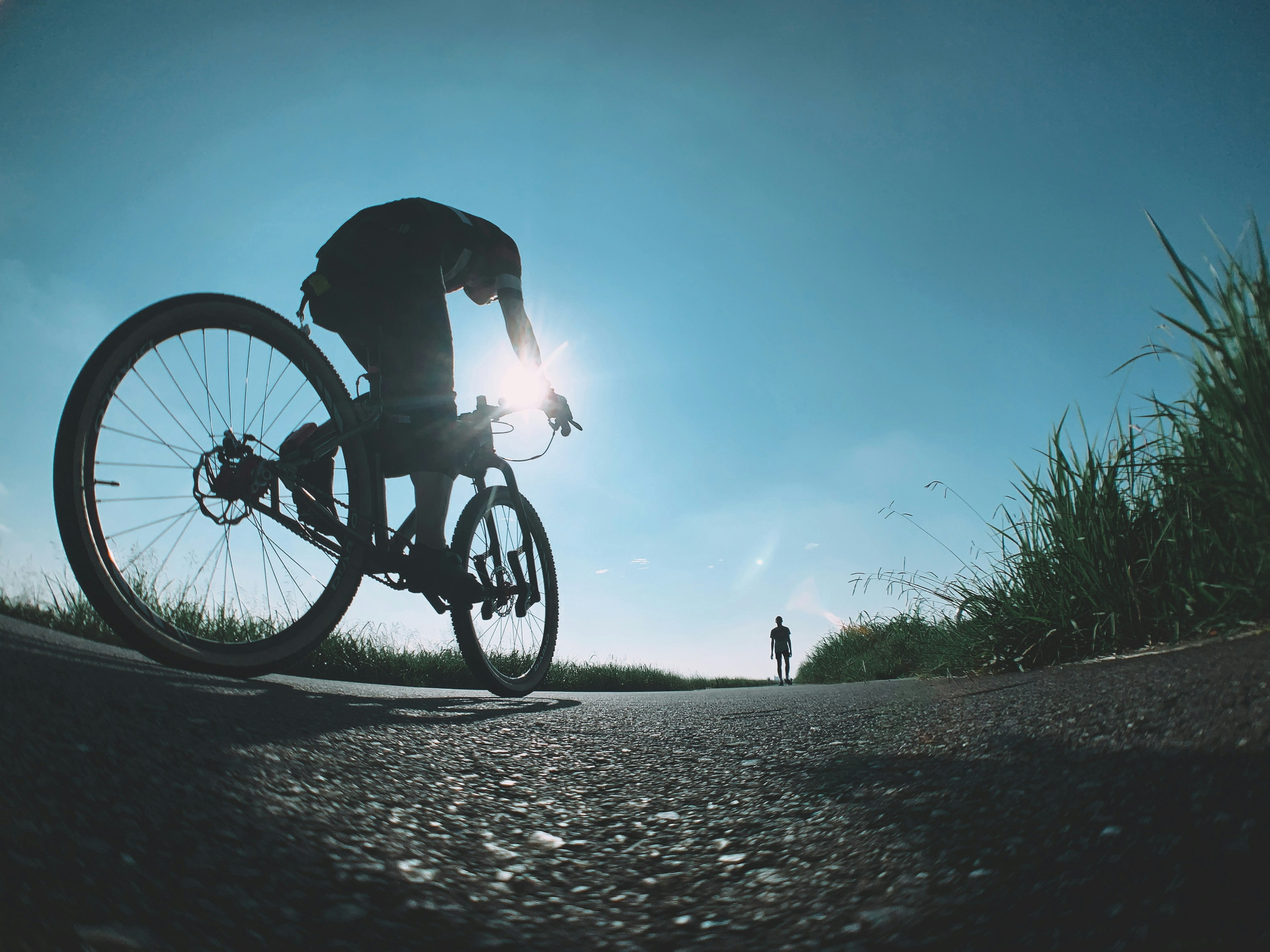 Silhouette einer Person auf einem Fahrrad vor blauem Himmel