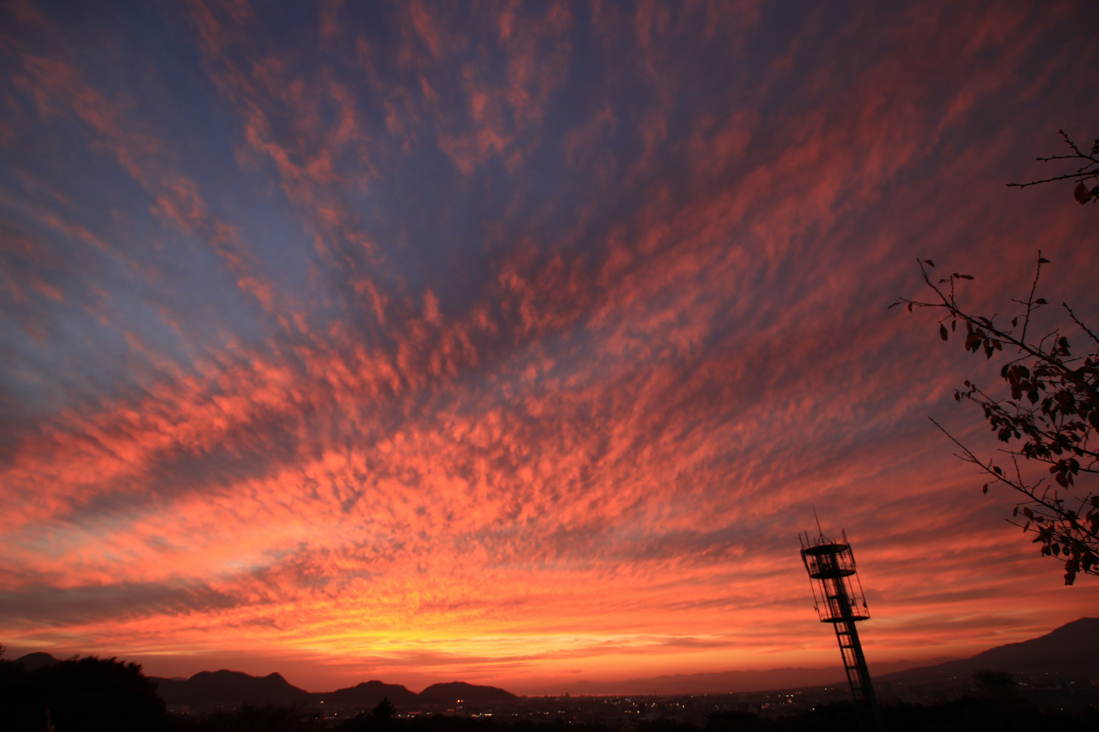 夕焼けの空に広がる赤とオレンジの雲と山々のシルエット