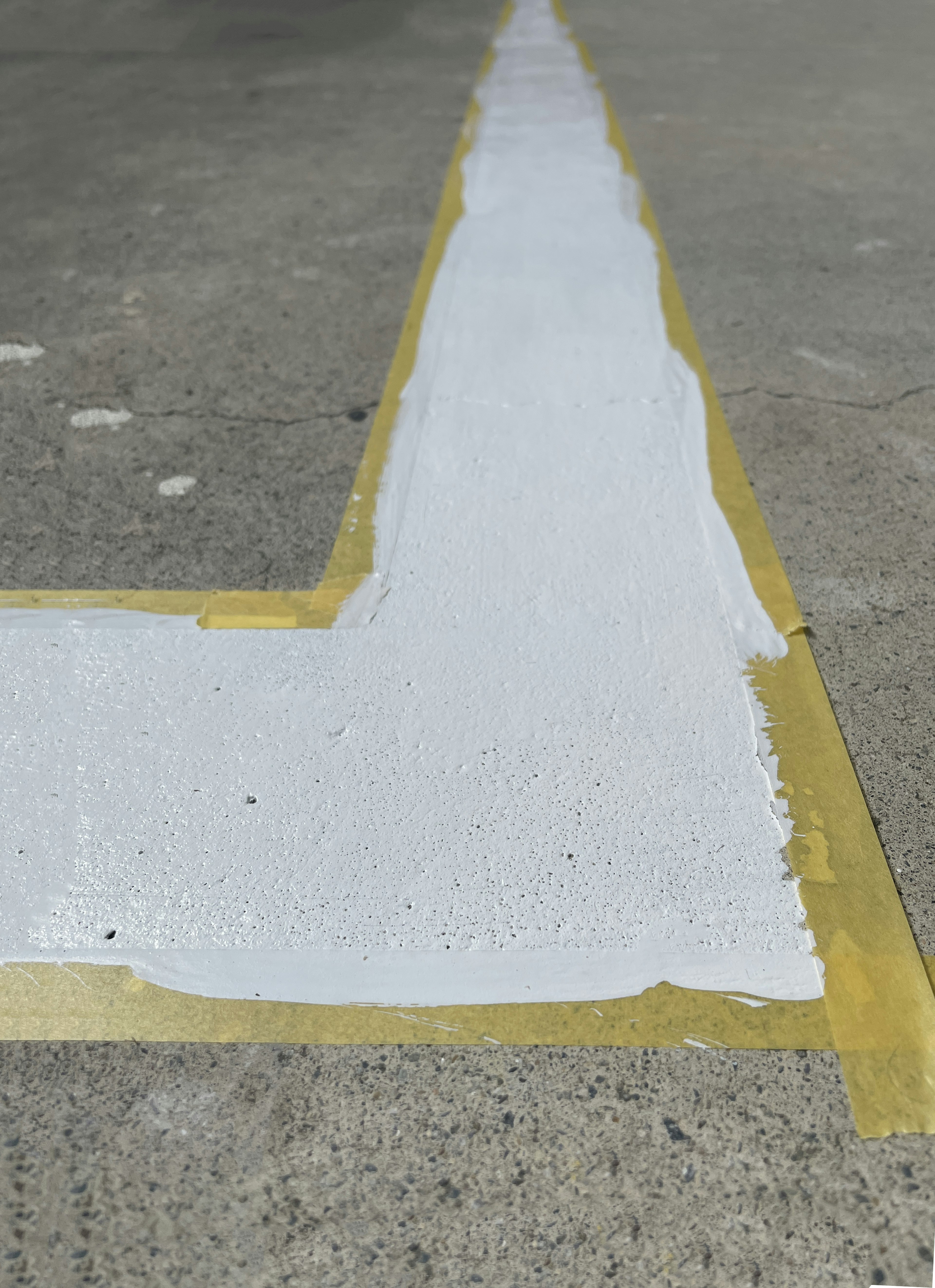 Close-up of a white line on concrete floor with masking tape