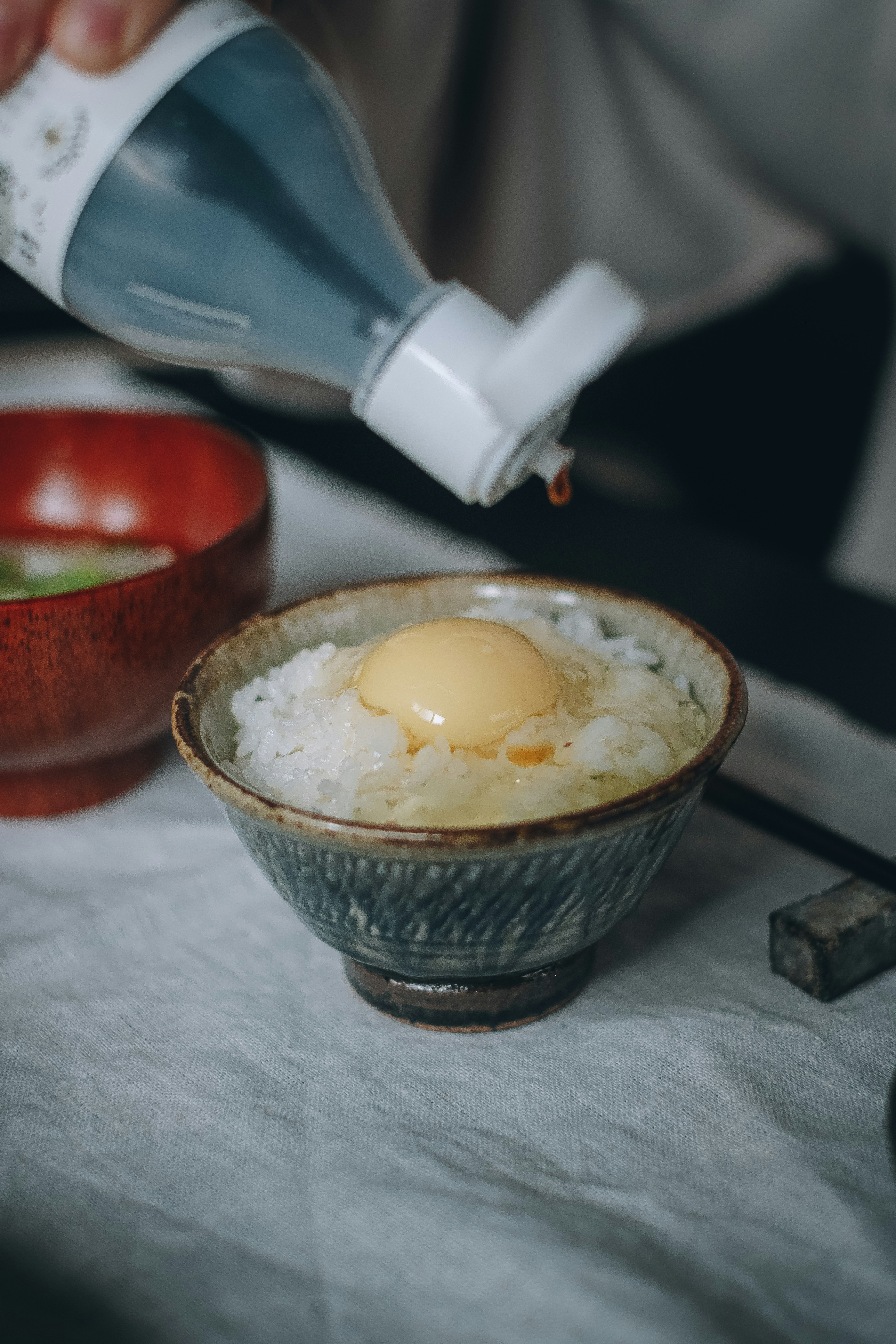 Versement de sauce sur un bol de riz garni d'un œuf