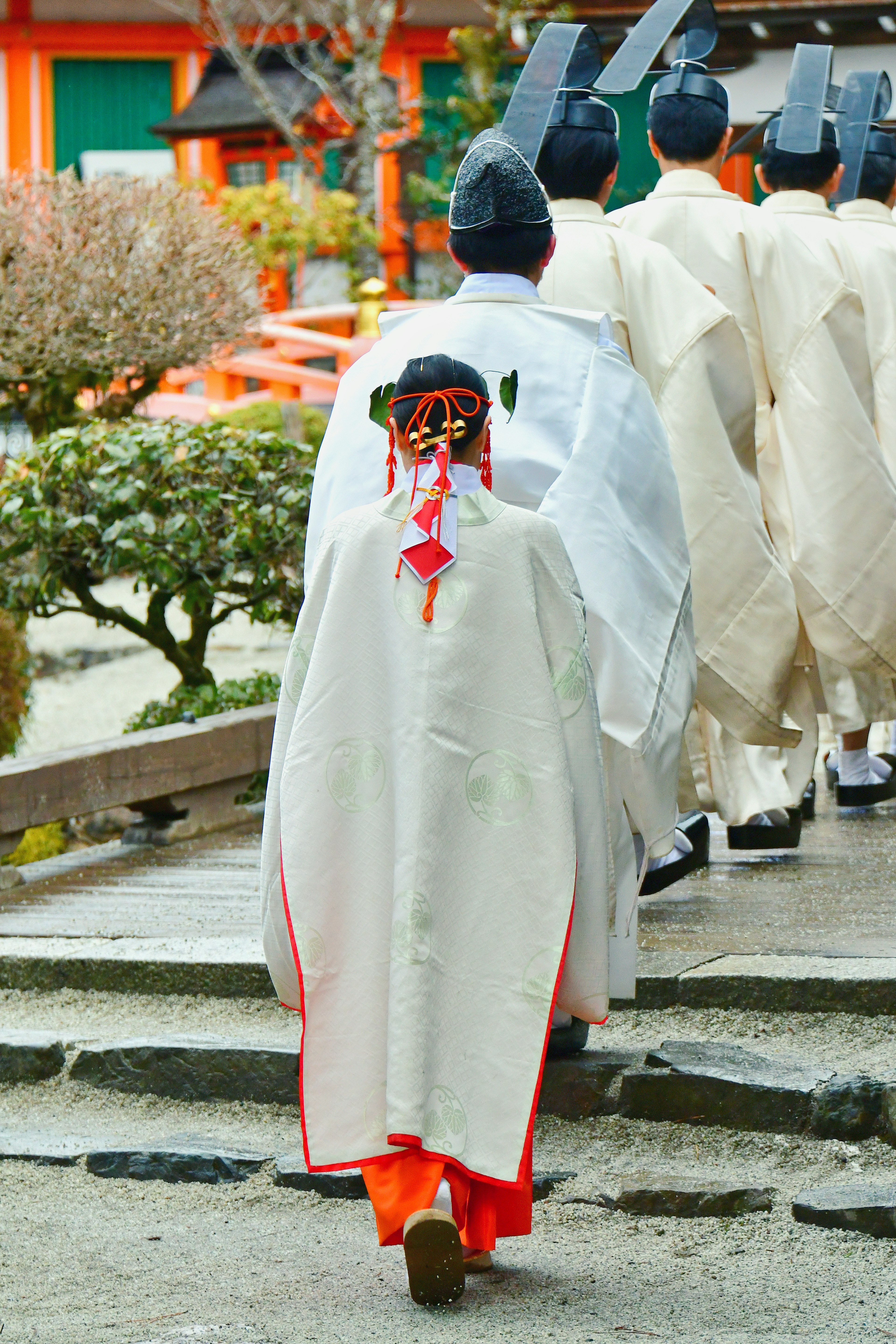 Individuo in abito bianco in testa a una processione con decorazioni rosse