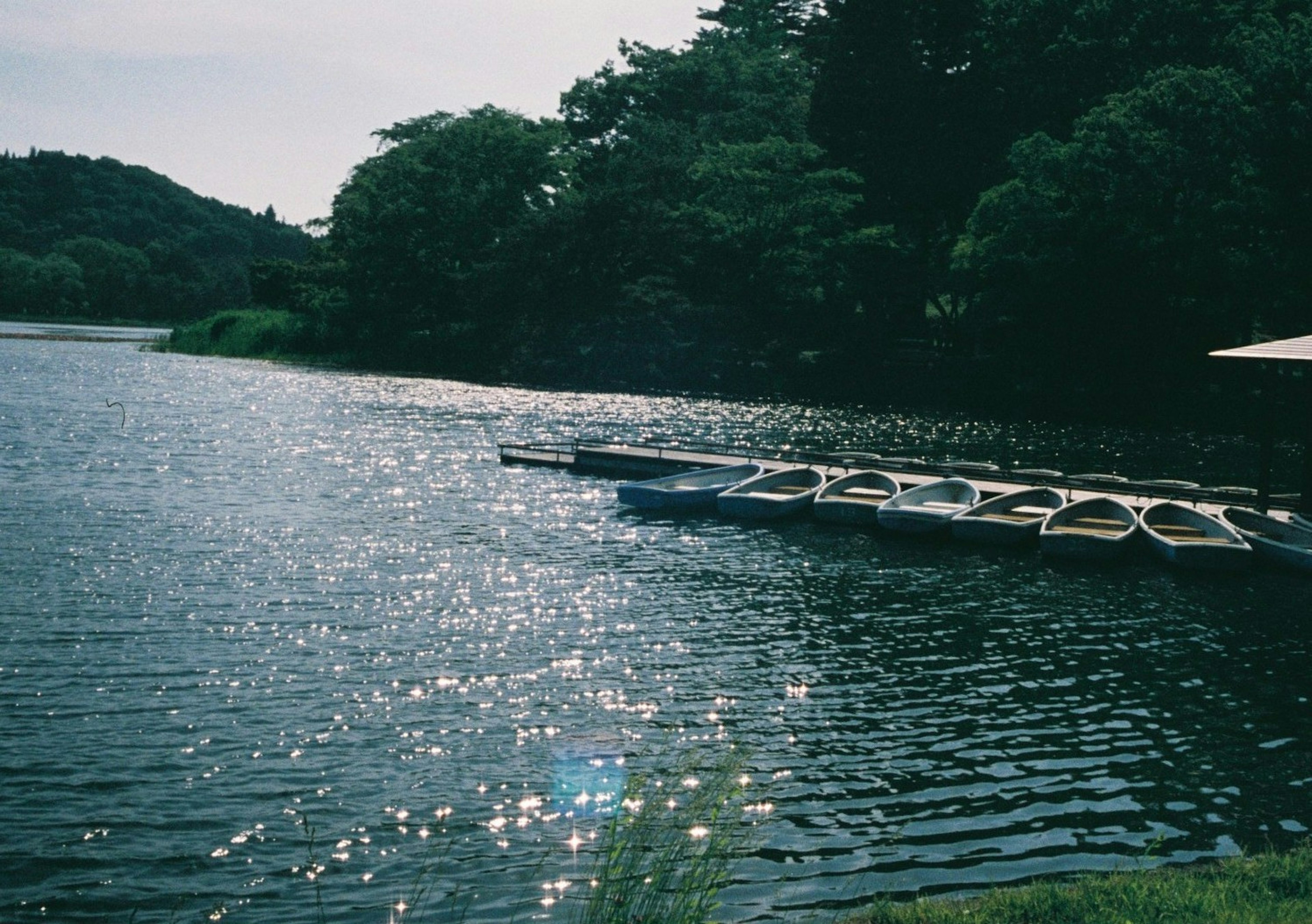 Ruhiger See mit schwimmenden Booten und funkelnder Wasseroberfläche