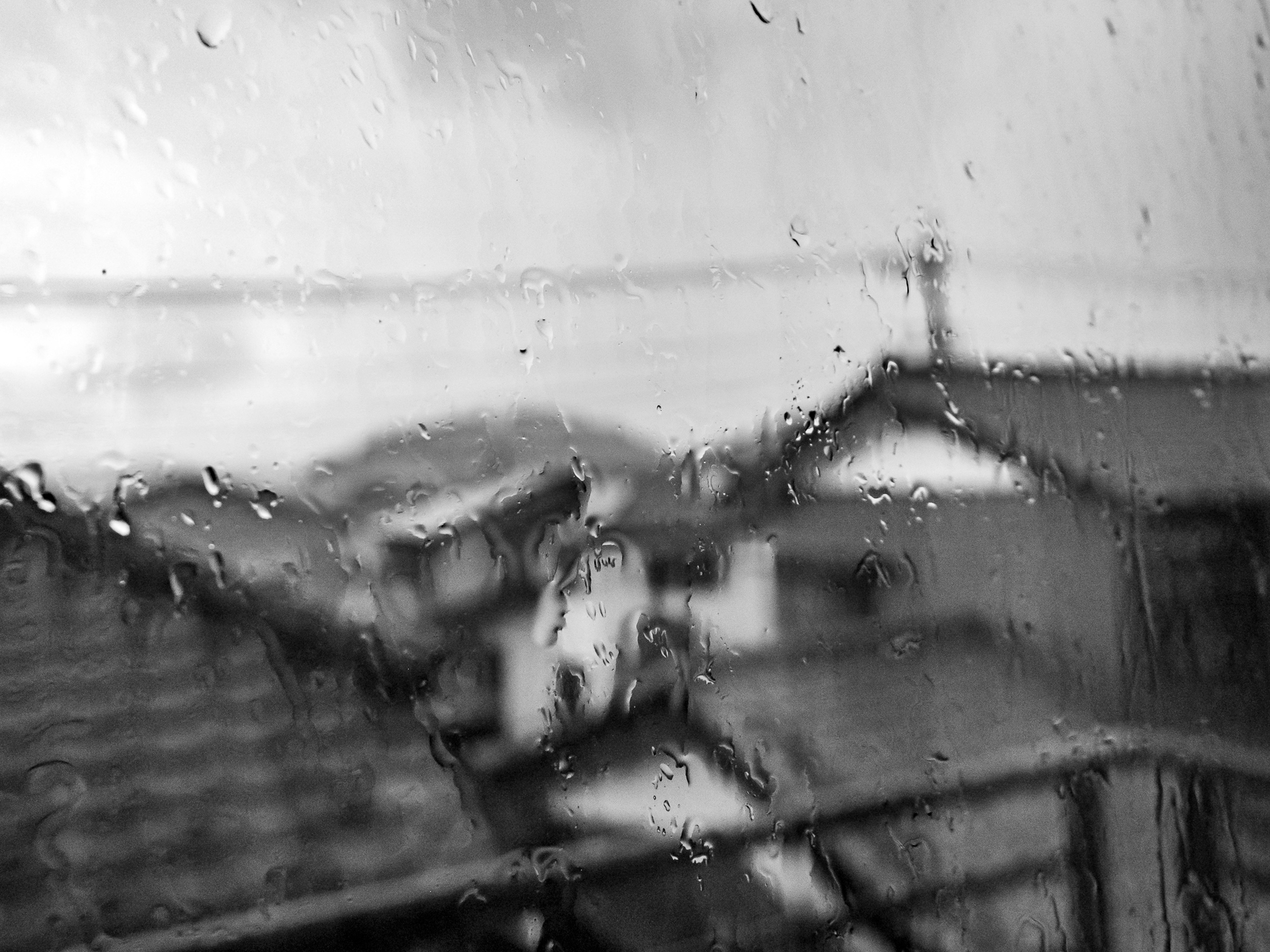 Blurred houses and mountains seen through a rain-soaked window