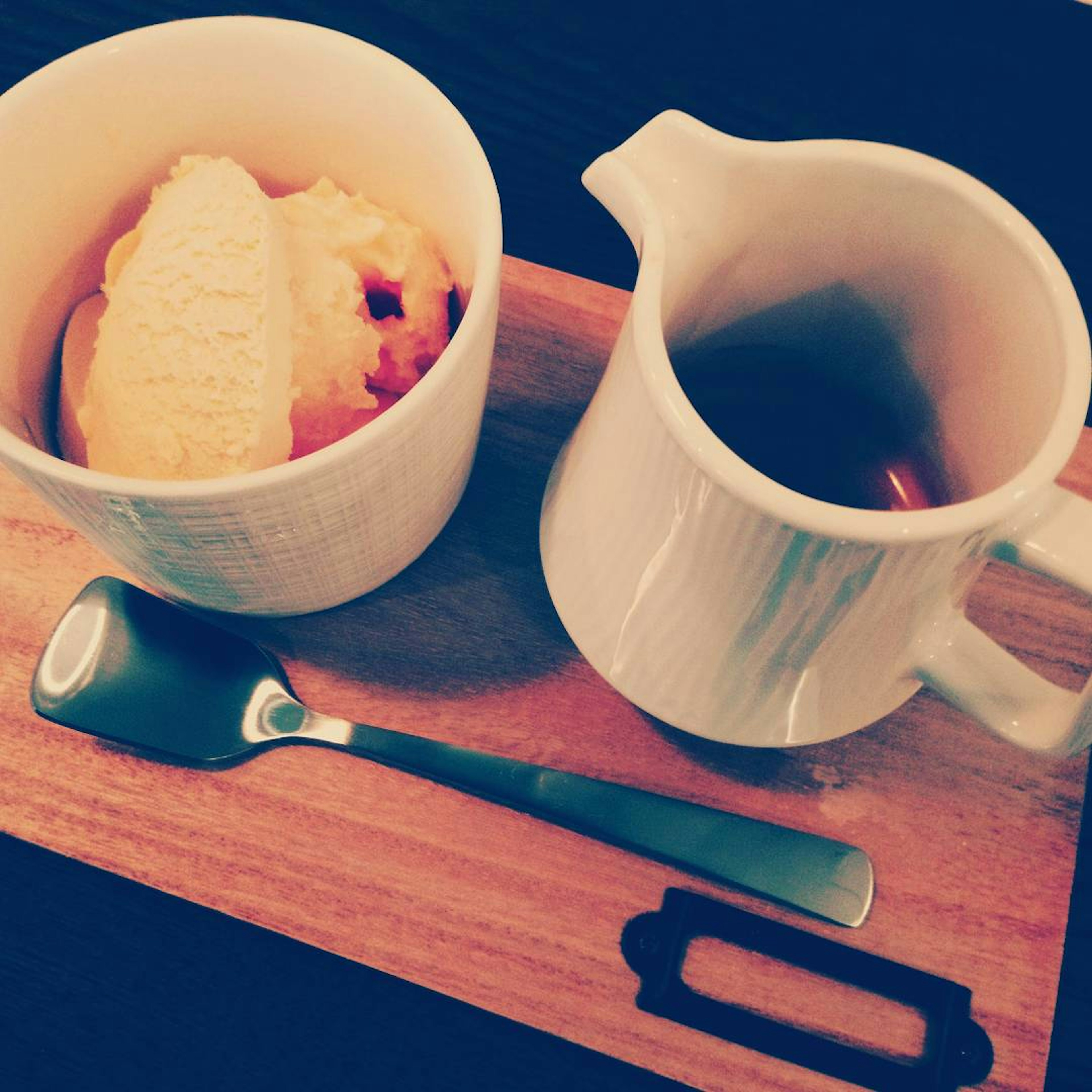 A bowl of ice cream and a teapot on a wooden tray