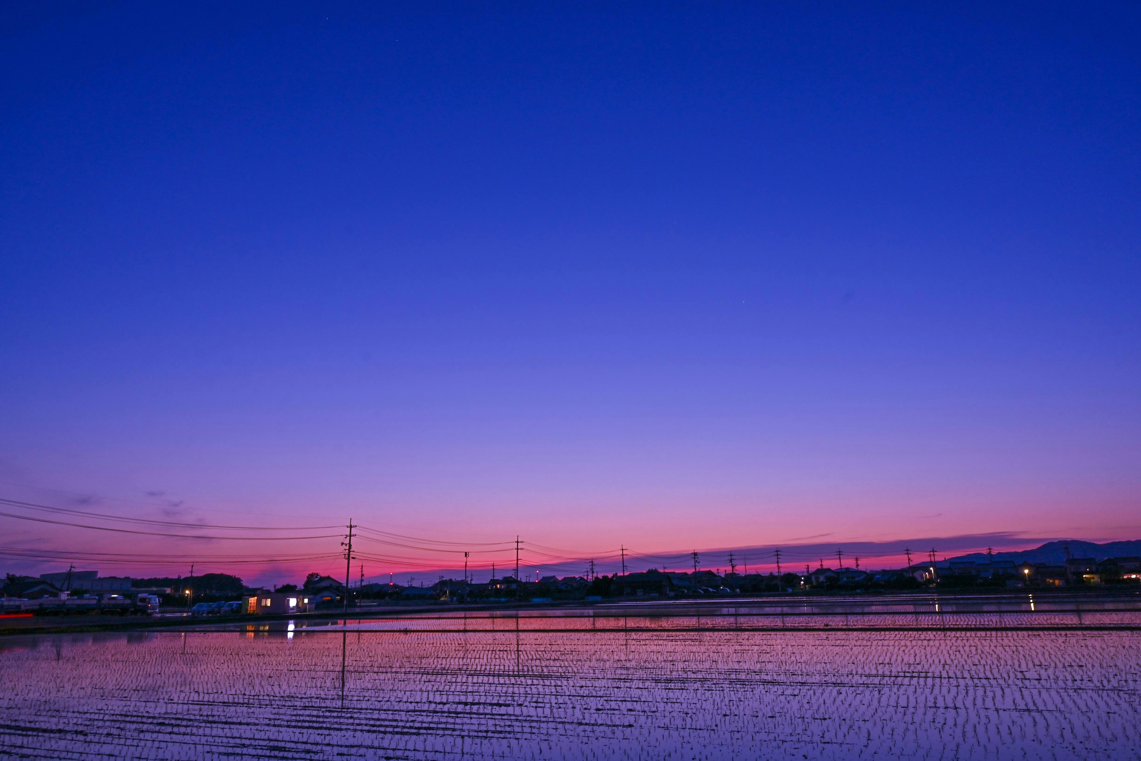 Schöner Farbverlauf von Blau und Lila beim Sonnenuntergang über einem See und der umliegenden Landschaft