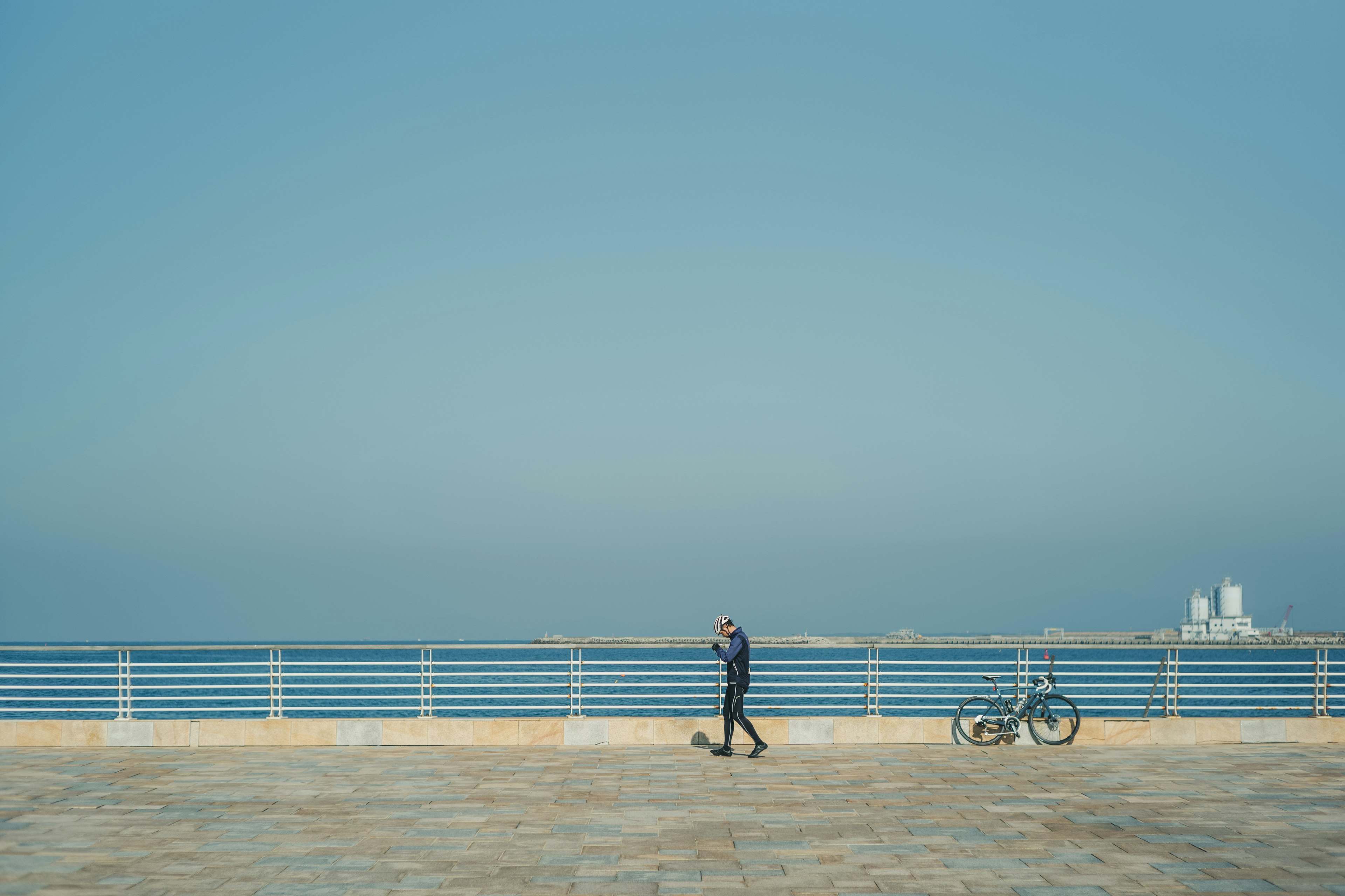 青い海と空の下で散歩する人物と自転車