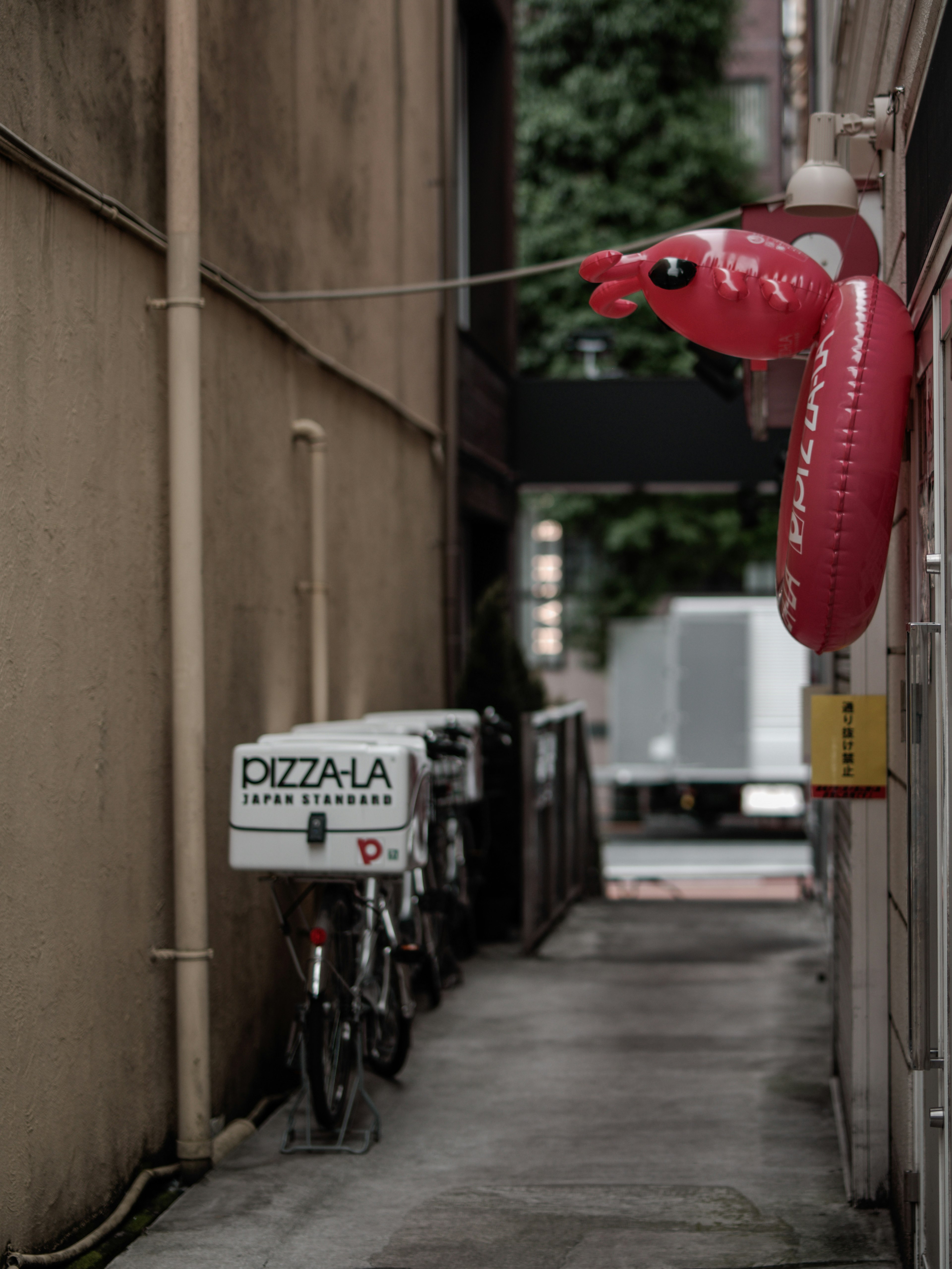 Vicolo stretto con una bicicletta per consegna di pizza e una balena gonfiabile rossa