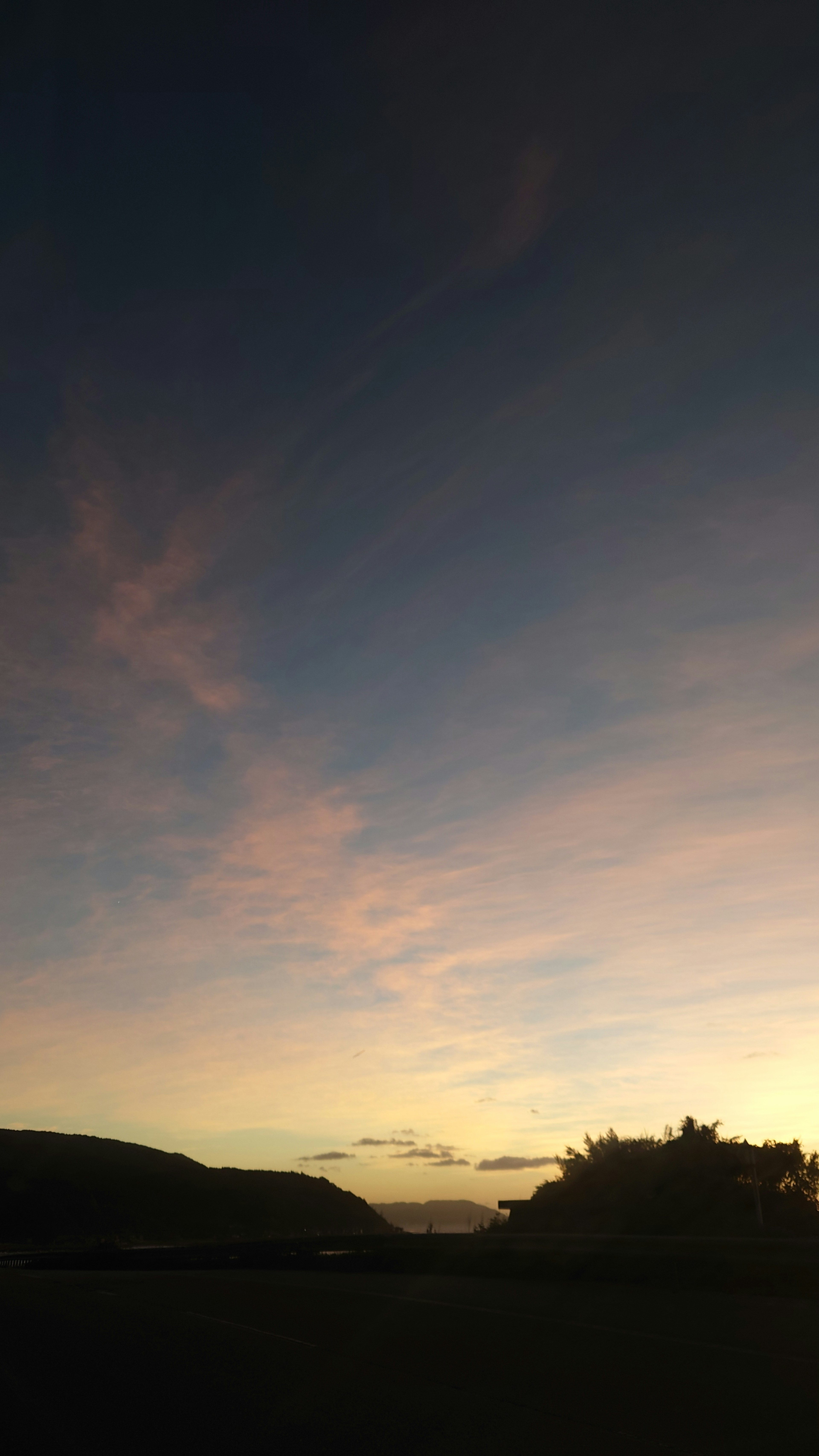 Twilight sky with silhouetted trees and hills