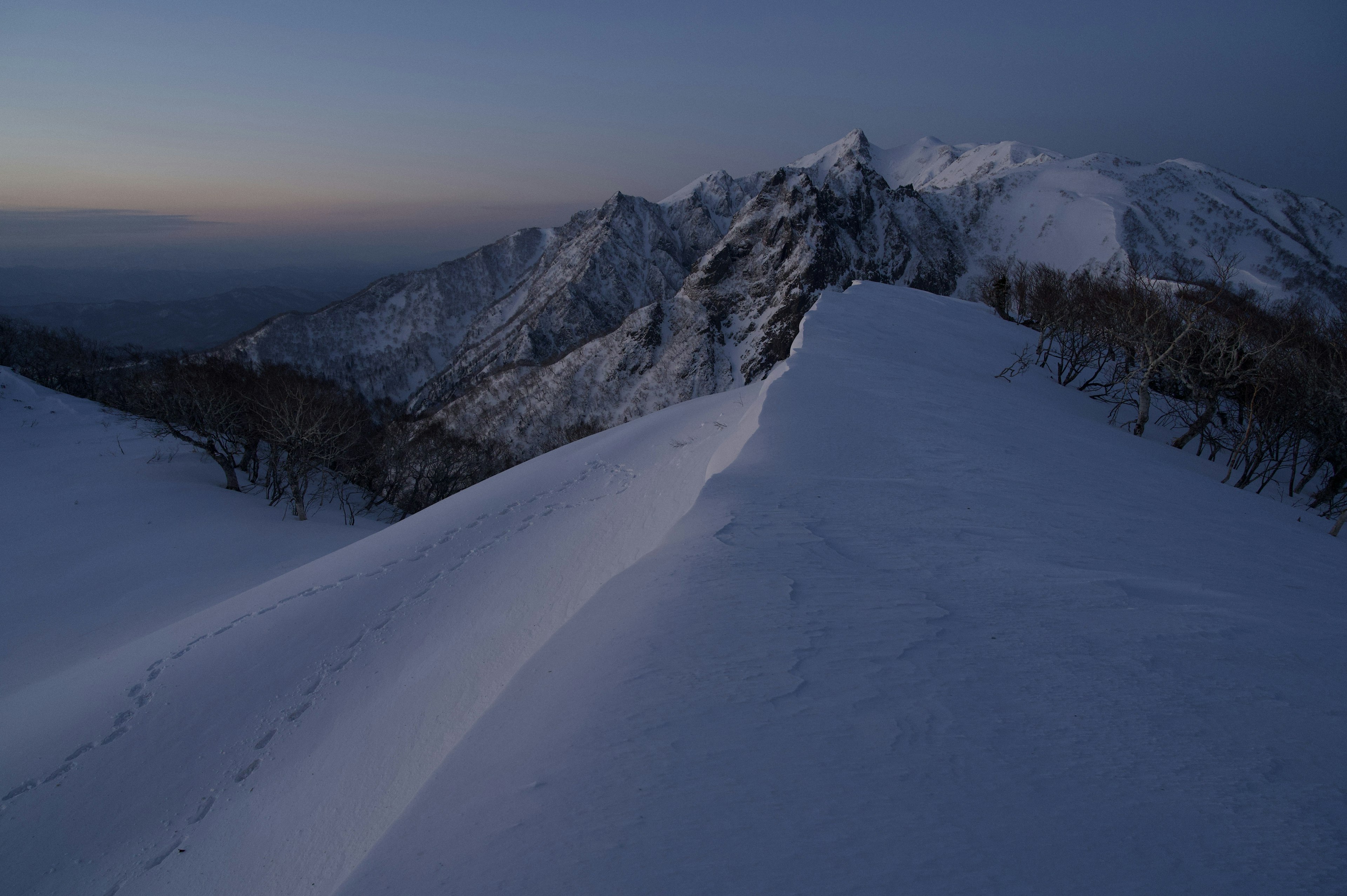 Paesaggio montano coperto di neve con luce crepuscolare tranquilla