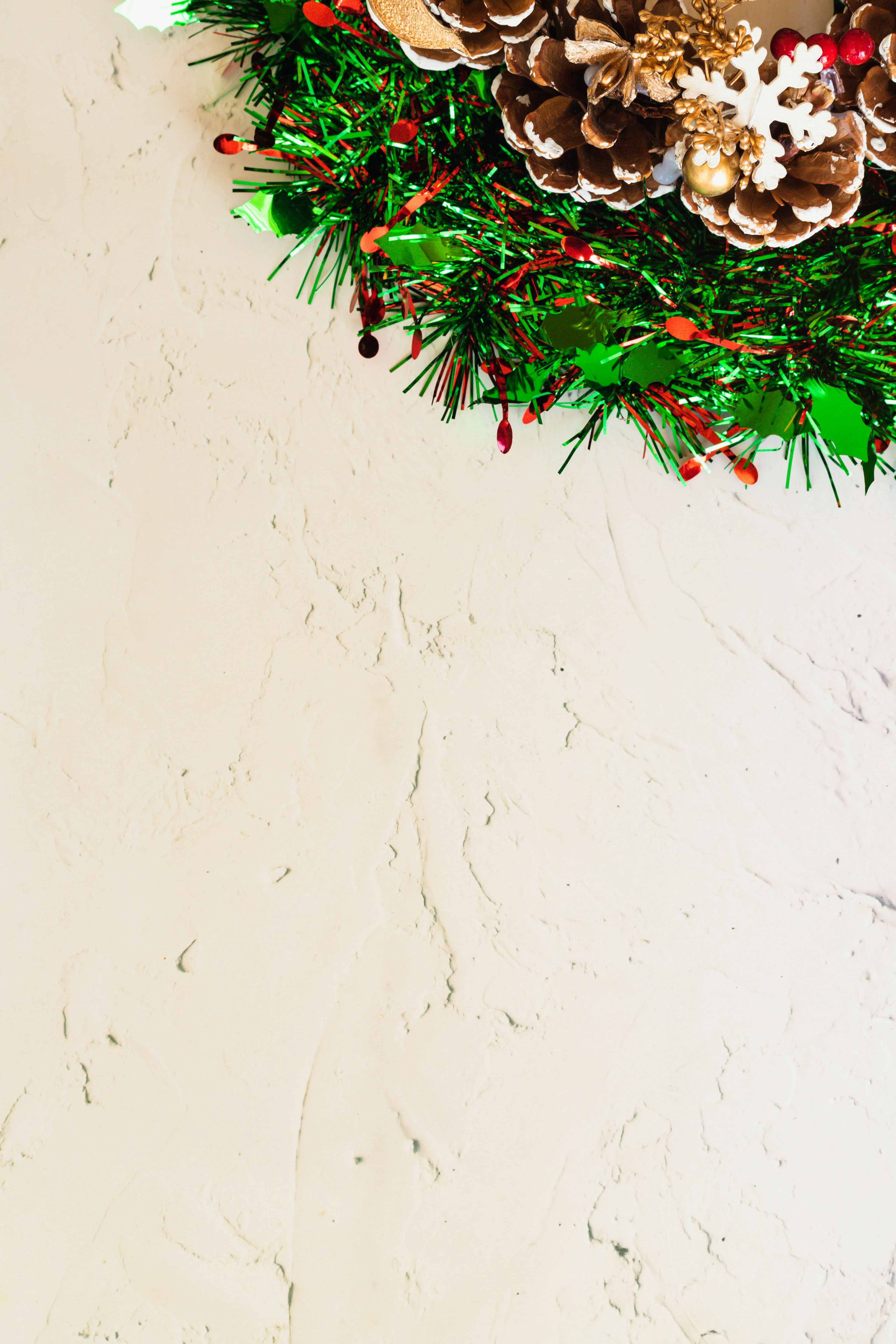 Christmas wreath with pine cones and greenery on a textured wall