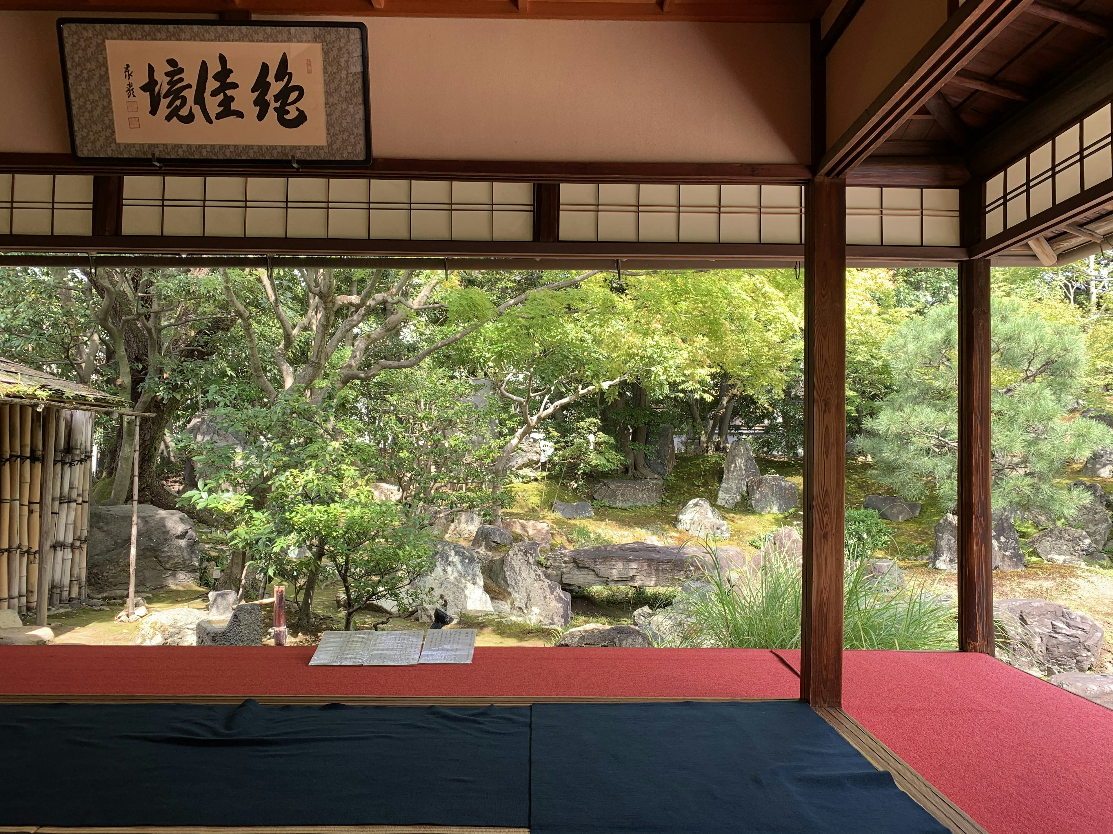 Vue d'un jardin japonais depuis une pièce traditionnelle avec de la verdure et des pierres