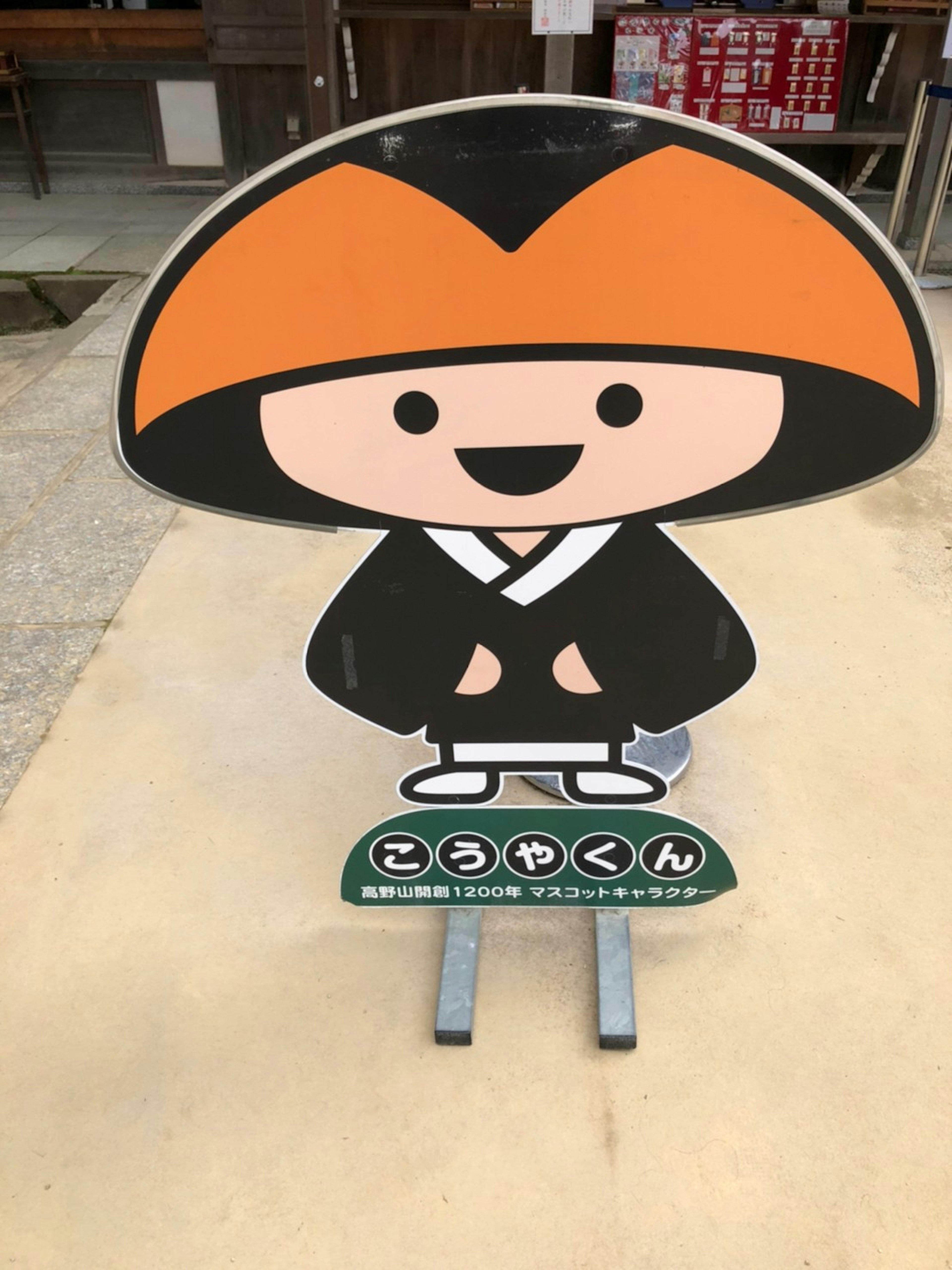 Papan karakter lucu dengan topi oranye dan jubah hitam