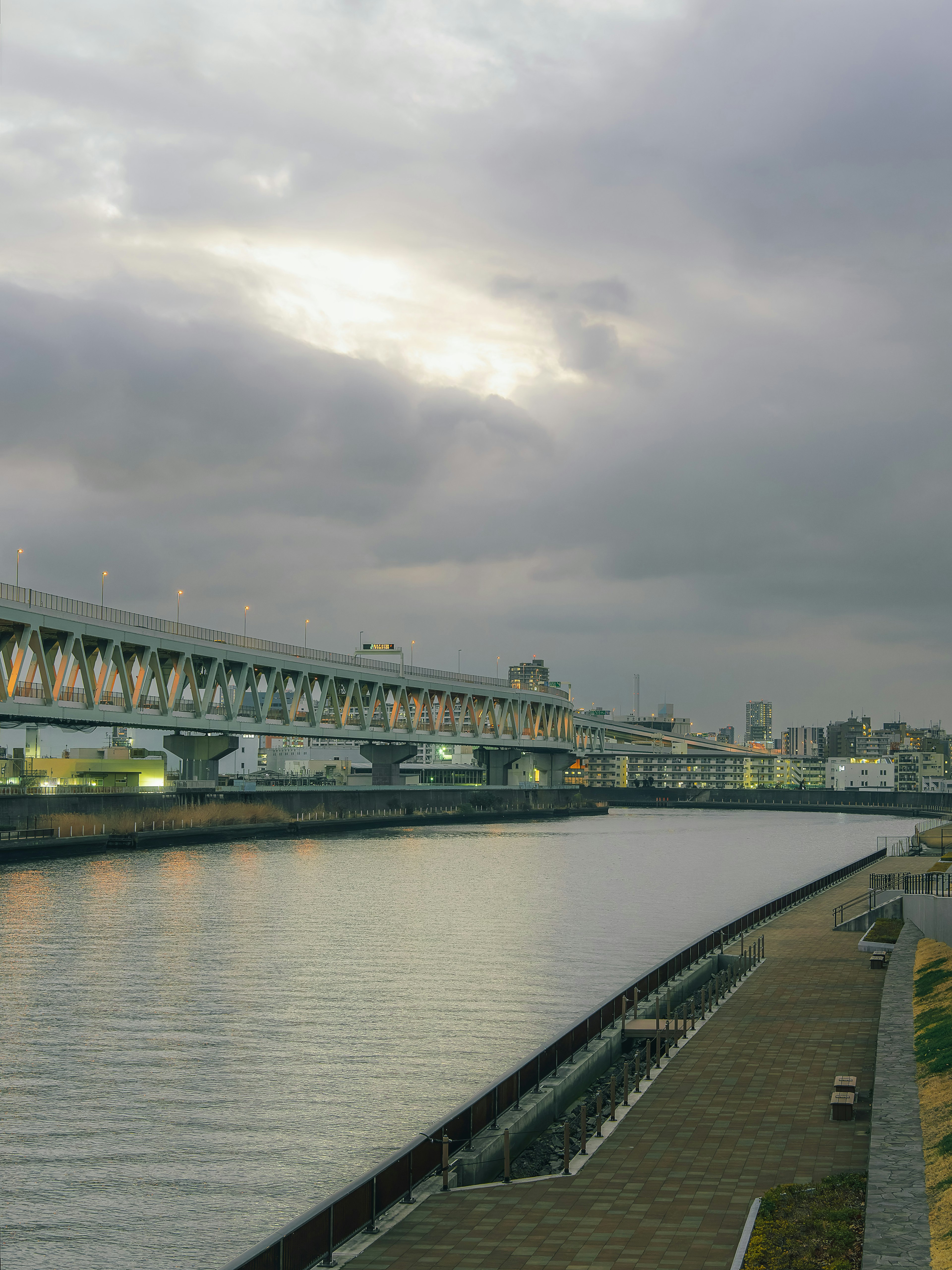 Fluss- und Brückenszene bei Dämmerung mit bewölktem Himmel