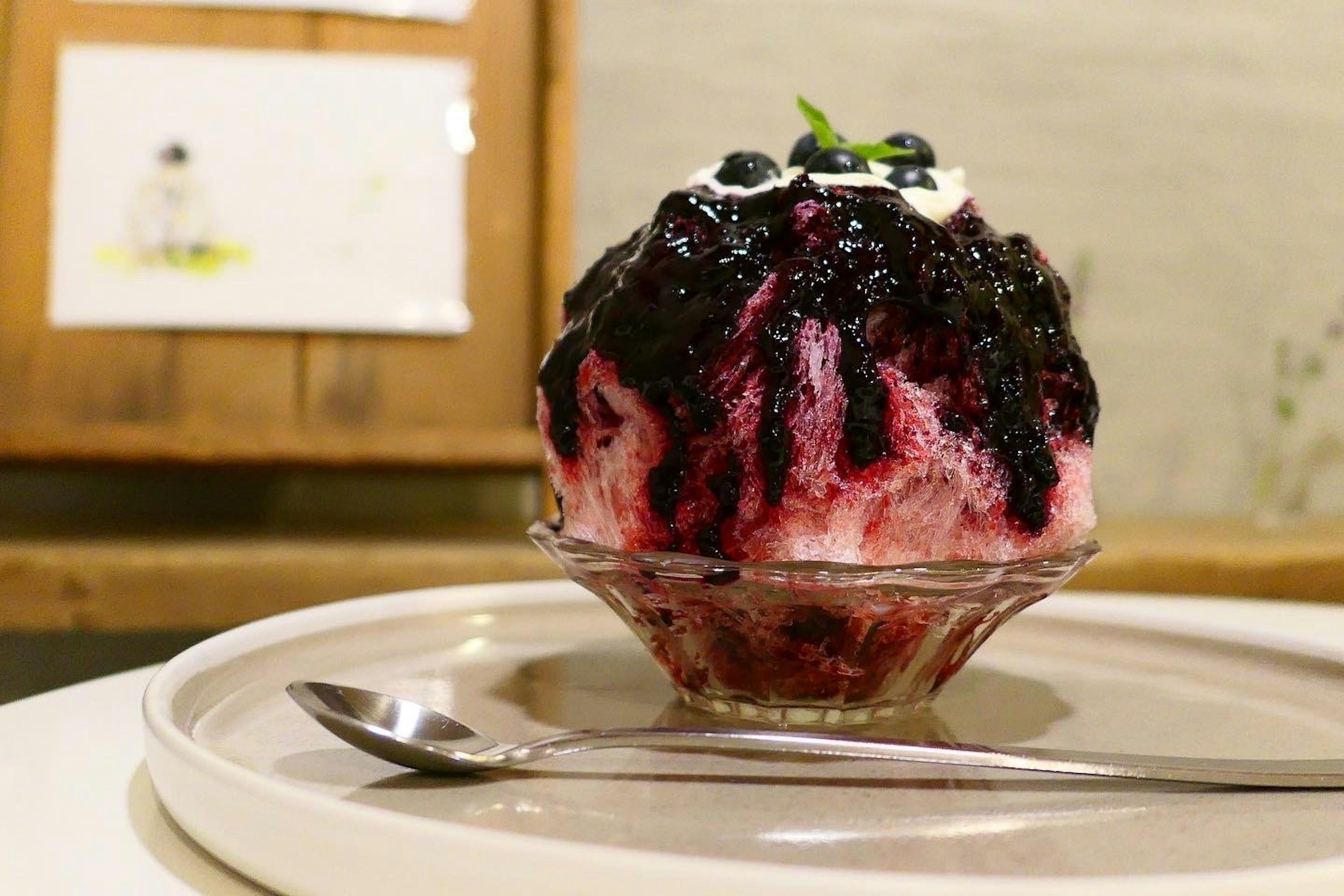 Shaved ice dessert topped with blueberry sauce and mint leaves