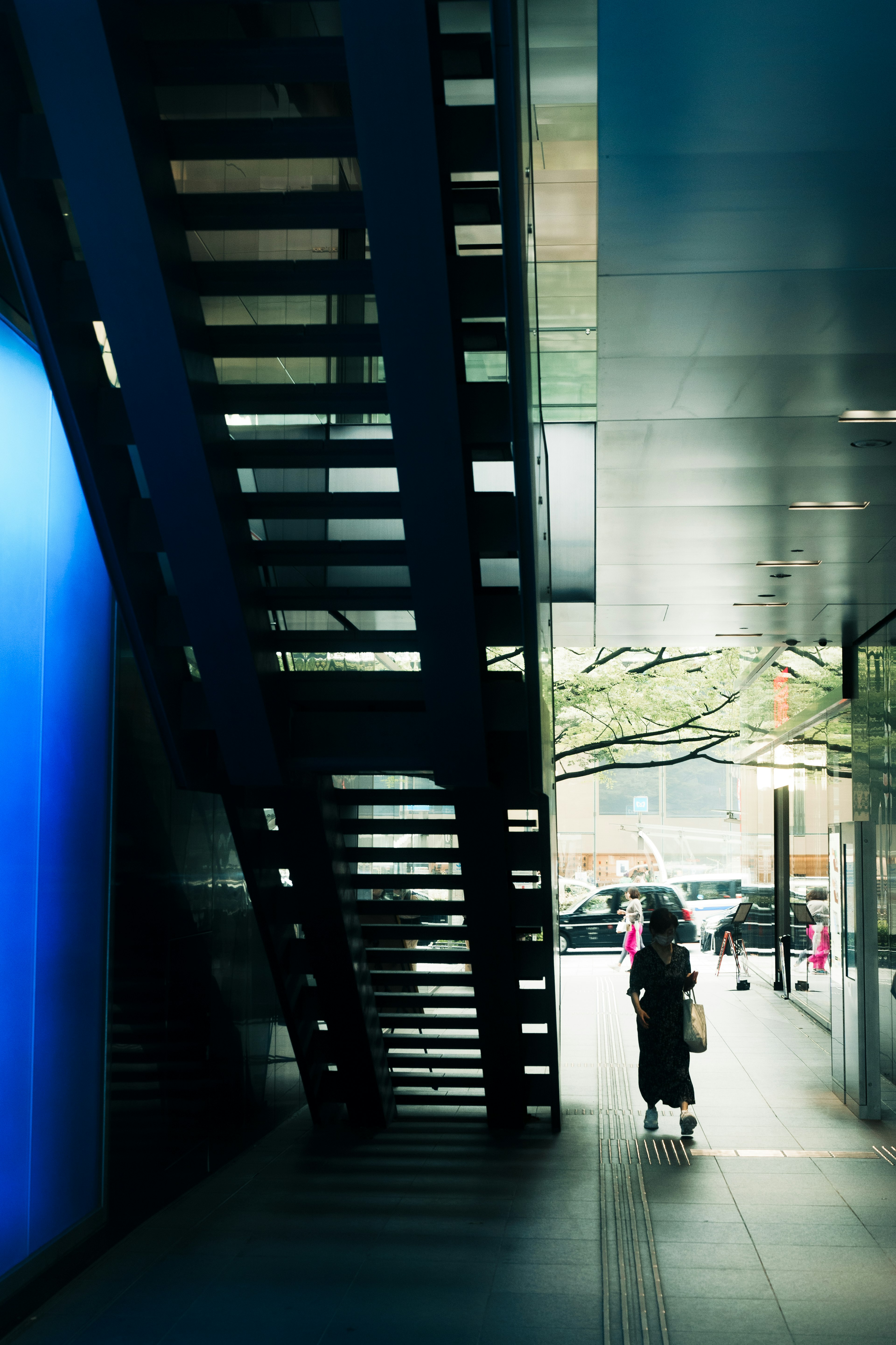 Una donna in una scena urbana con un muro blu e scale