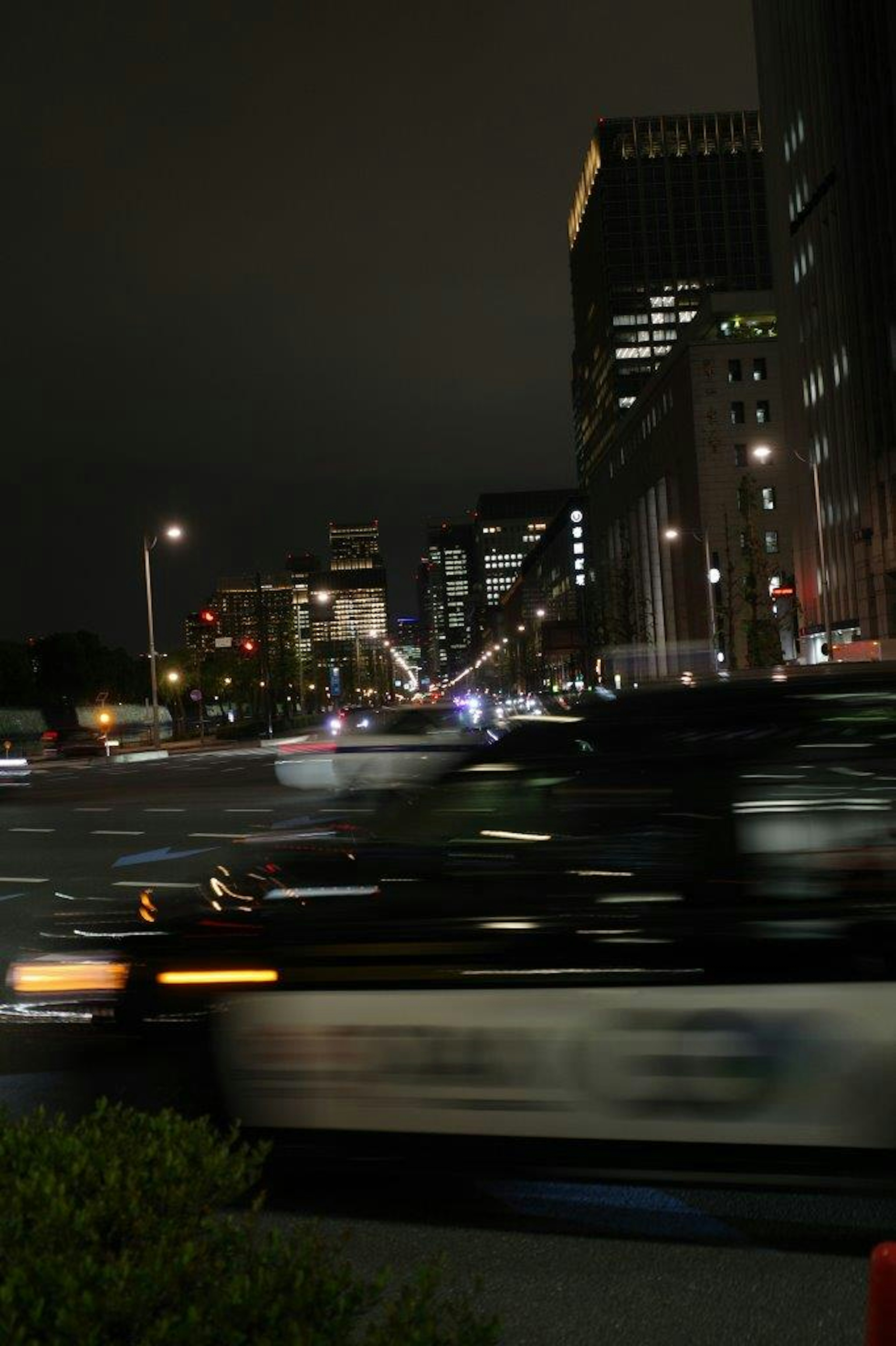 Auto della polizia che sfreccia per le strade della città di notte con edifici sfocati