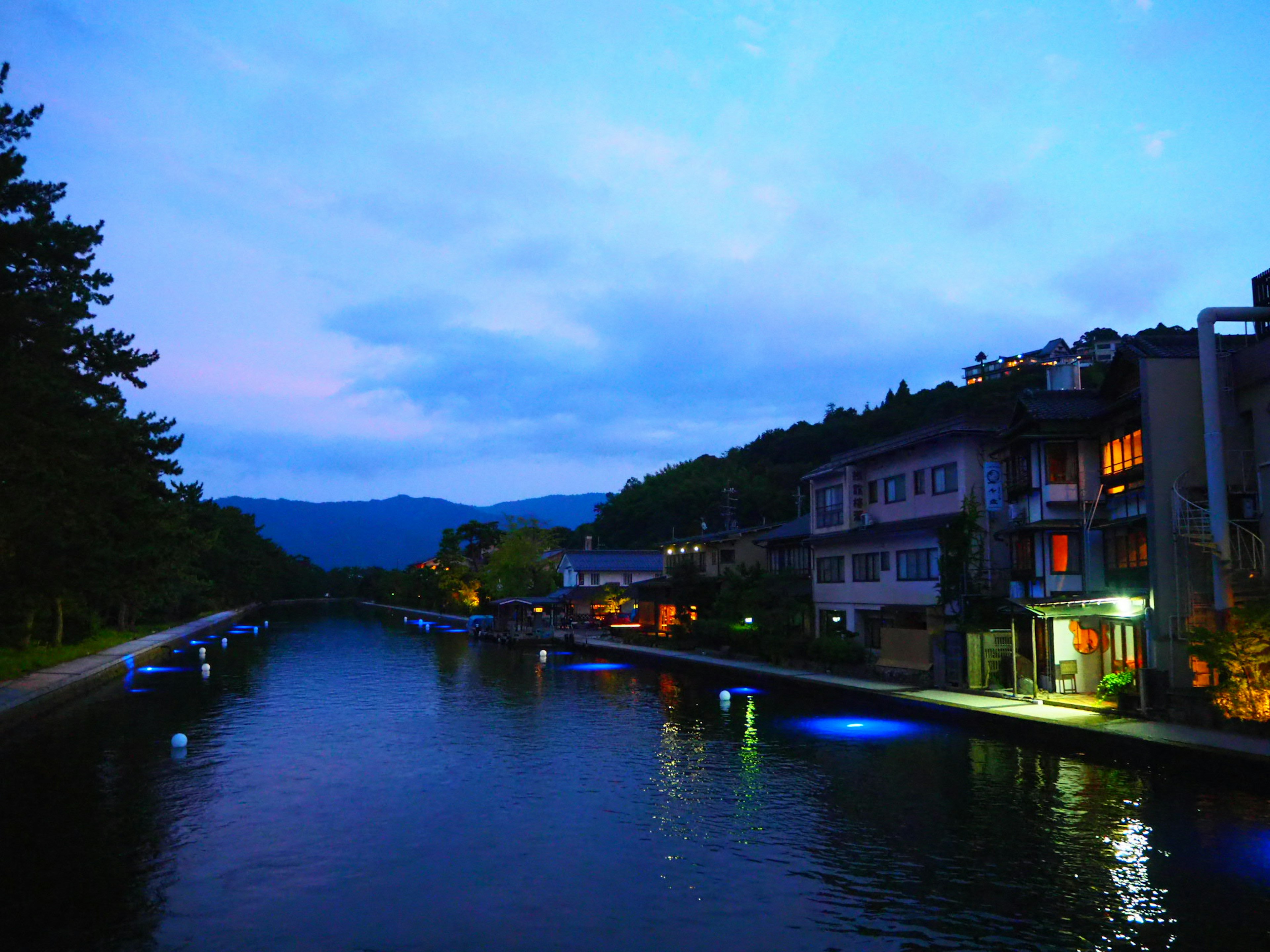 Vista escénica del río con edificios iluminados al anochecer