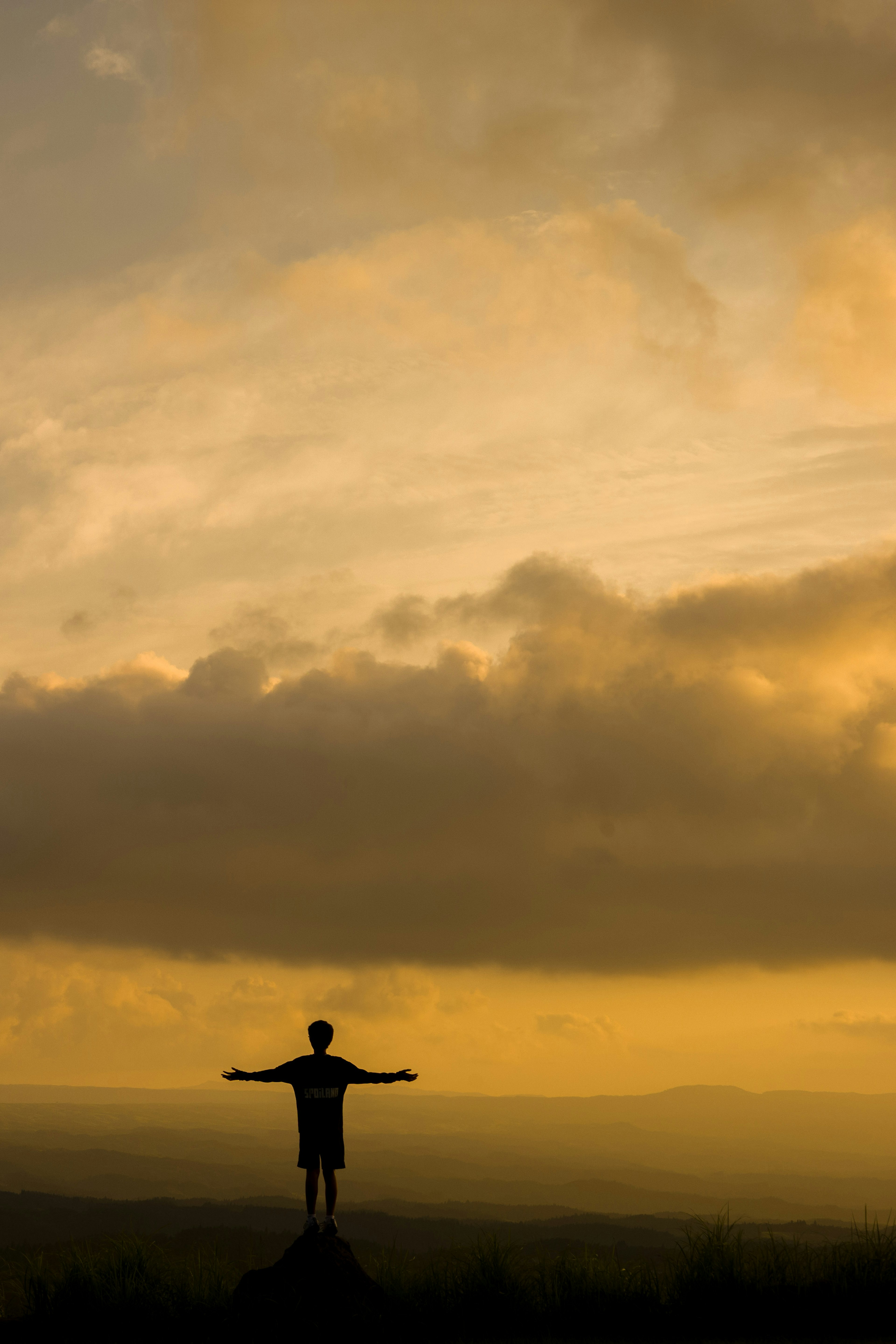 Silhouette d'une personne se tenant devant un ciel au coucher de soleil