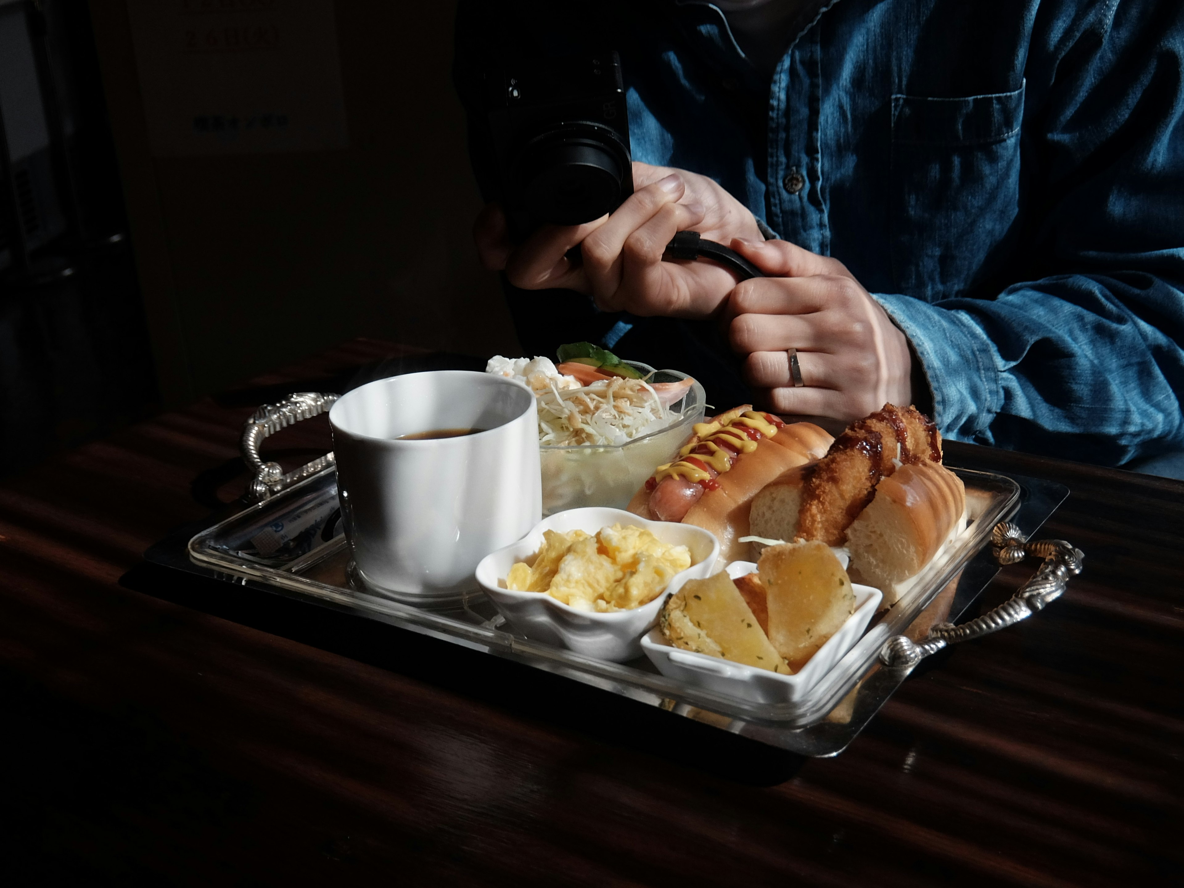 Una mano che tiene una macchina fotografica sopra un vassoio di cibo con riso, pane e dessert