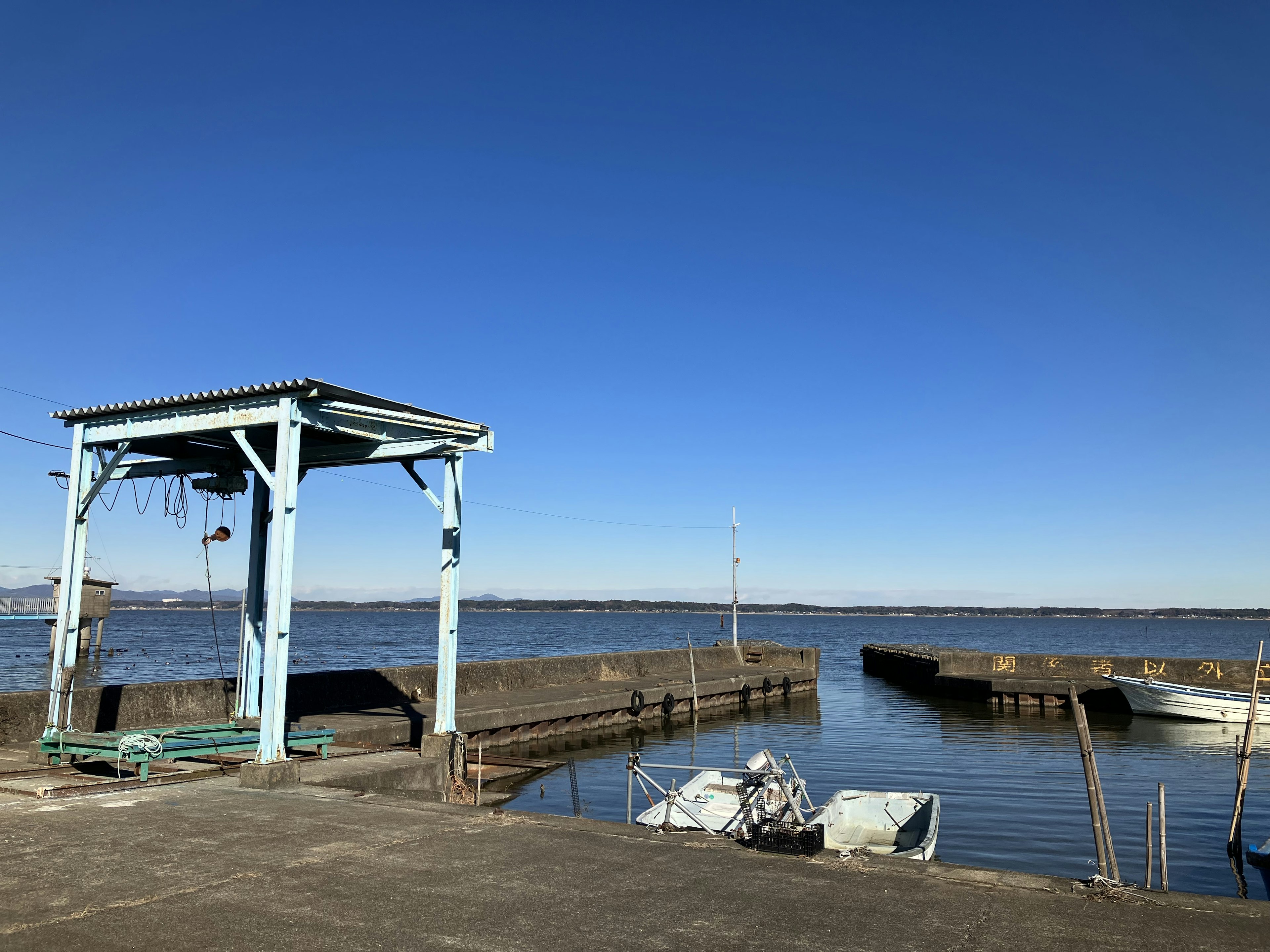 Vista escénica de un puerto bajo un cielo azul con un cobertizo y pequeños botes